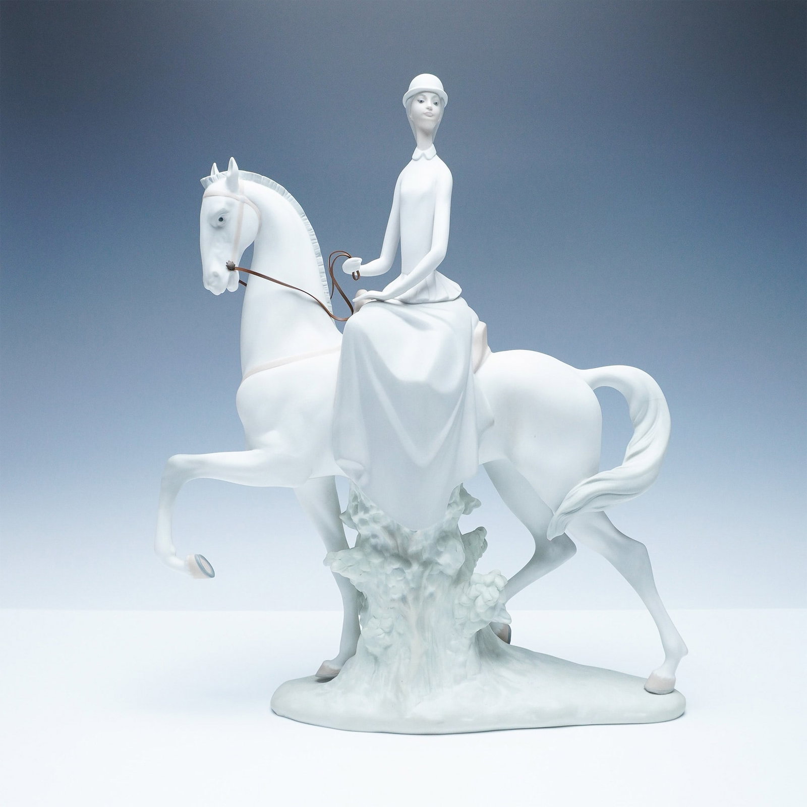 Nao by Lladro Porcelain Figurine, Female Equestrian: Nao by Lladro matter porcelain figurine featuring an elegant female equestrian riding side-saddle on a gracefully posed horse. Crafted in soft pastel tones with a smooth matte finish, this finely deta
