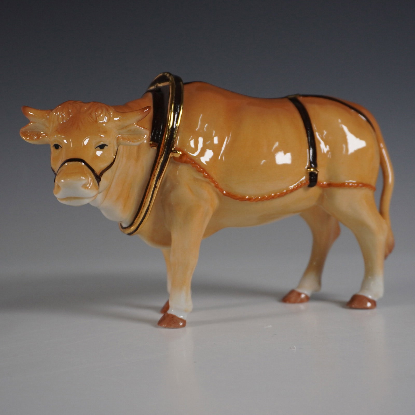 Royal Doulton Holiday Traditions Nativity Oxen Figurine: A Royal Doulton Holiday Traditions Nativity Oxen figurine, beautifully handcrafted and hand-decorated in fine bone china. This exquisite piece is accented with 22-karat gold, highlighting the intricat