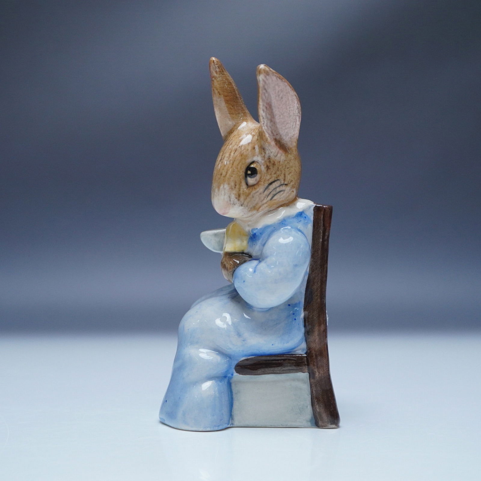 Royal Albert Beatrix Potter Figurine, Cottontail: This Royal Albert Beatrix Potter figurine depicts Cottontail, one of Beatrix Potter's beloved characters. Made of fine bone china, this collectible showcases Cottontail seated on a wooden chair, enjoy
