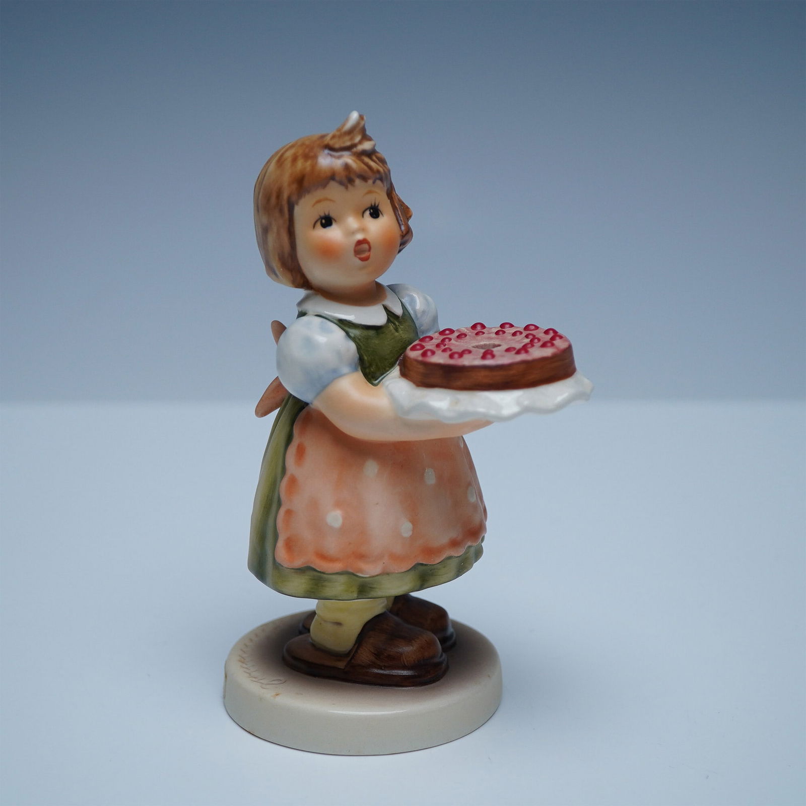 Goebel Hummel Porcelain Figurine, Birthday Candle: This figurine, is an Exclusive Special Edition No. 10 produced for members of the Goebel Collectors Club. This delightful piece features a young girl in a green dress and orange apron, holding a beaut
