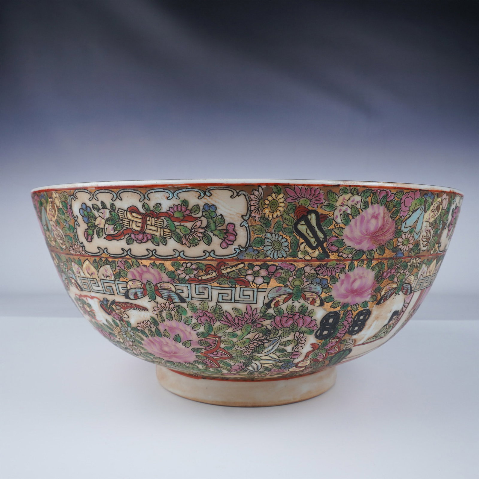 Chinese Porcelain Bowl, Famille Rose Design: This vibrant Chinese porcelain bowl features a Famille Rose design, characterized by intricate floral patterns and figural scenes rendered in vivid pinks, greens, and oranges. The exterior displays a 