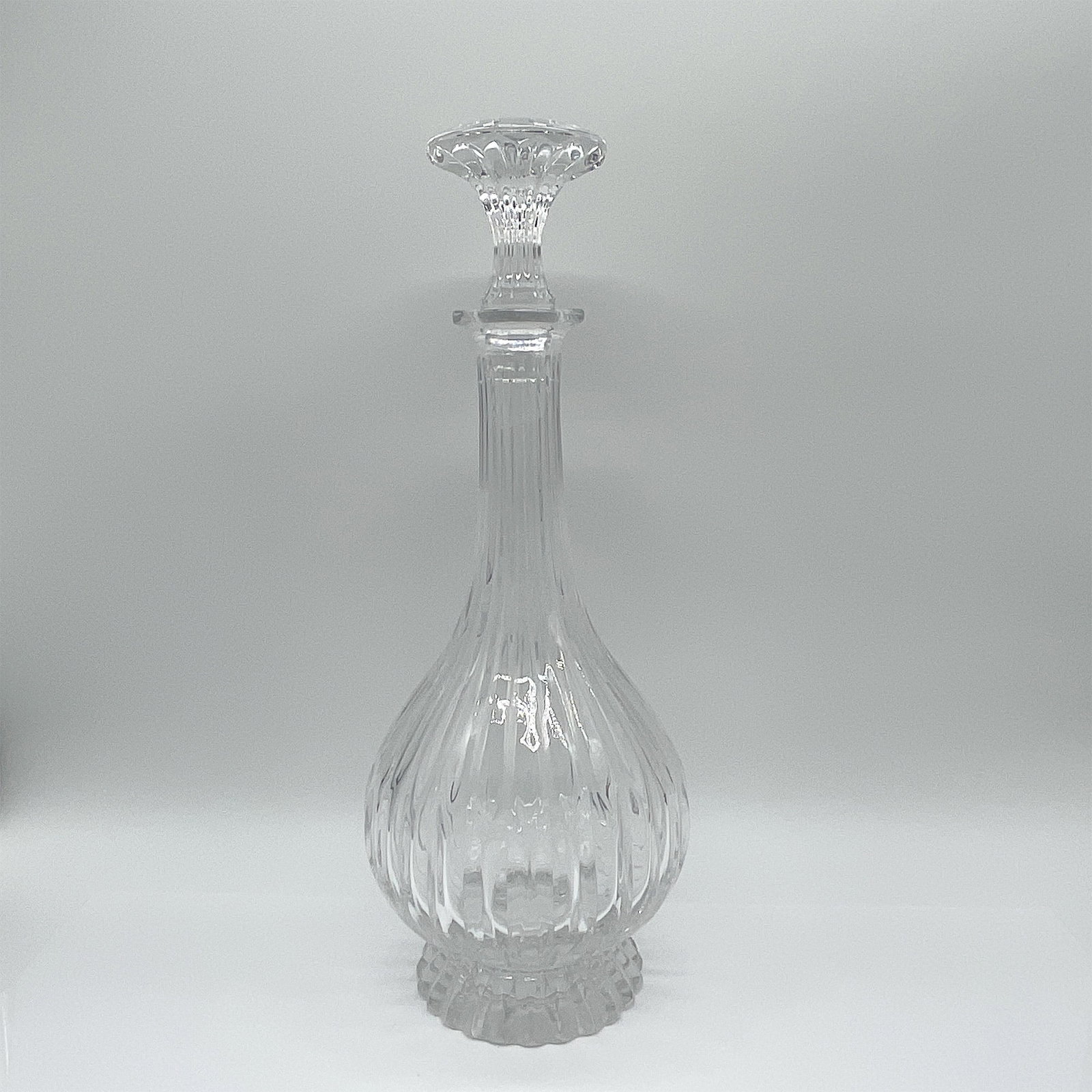 Art Glass Decanter with Stopper, Ribbed Design: Elegant art glass decanter featuring a ribbed body and stopper. This piece showcases a flared pedestal base and elongated neck, culminating in a finely detailed stopper that mirrors the ribbed design.