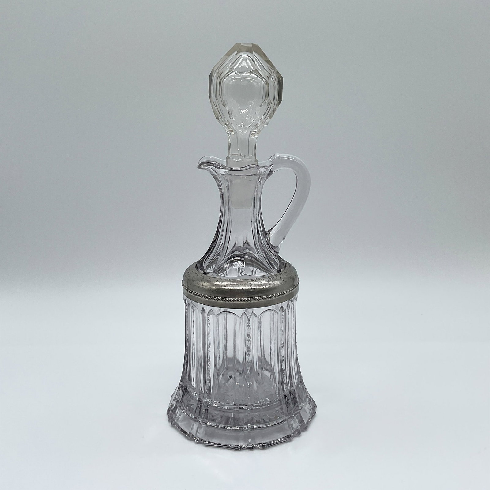 Cut Glass Decanter with Silver-Toned Collar and Stopper: This elegant cut glass decanter stands 10 inches tall and features a beautifully faceted design with vertical ribbing and intricate detailing. The piece is accented with a silver-toned collar that enh