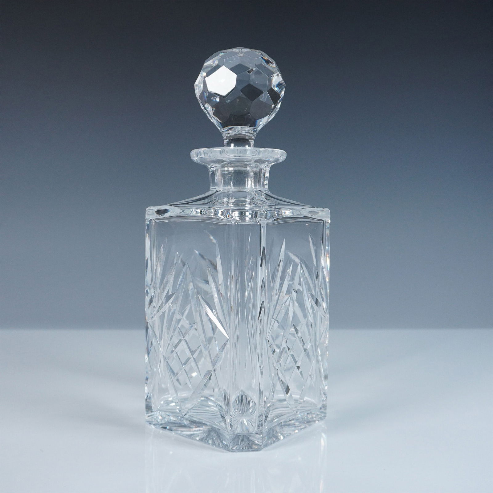 Thomas Webb Crystal Decanter with Stopper: Elegant crystal decanter by Thomas Webb of England, featuring a finely cut geometric pattern that enhances its reflective brilliance. The squared form is complemented by deeply cut crosshatched motifs