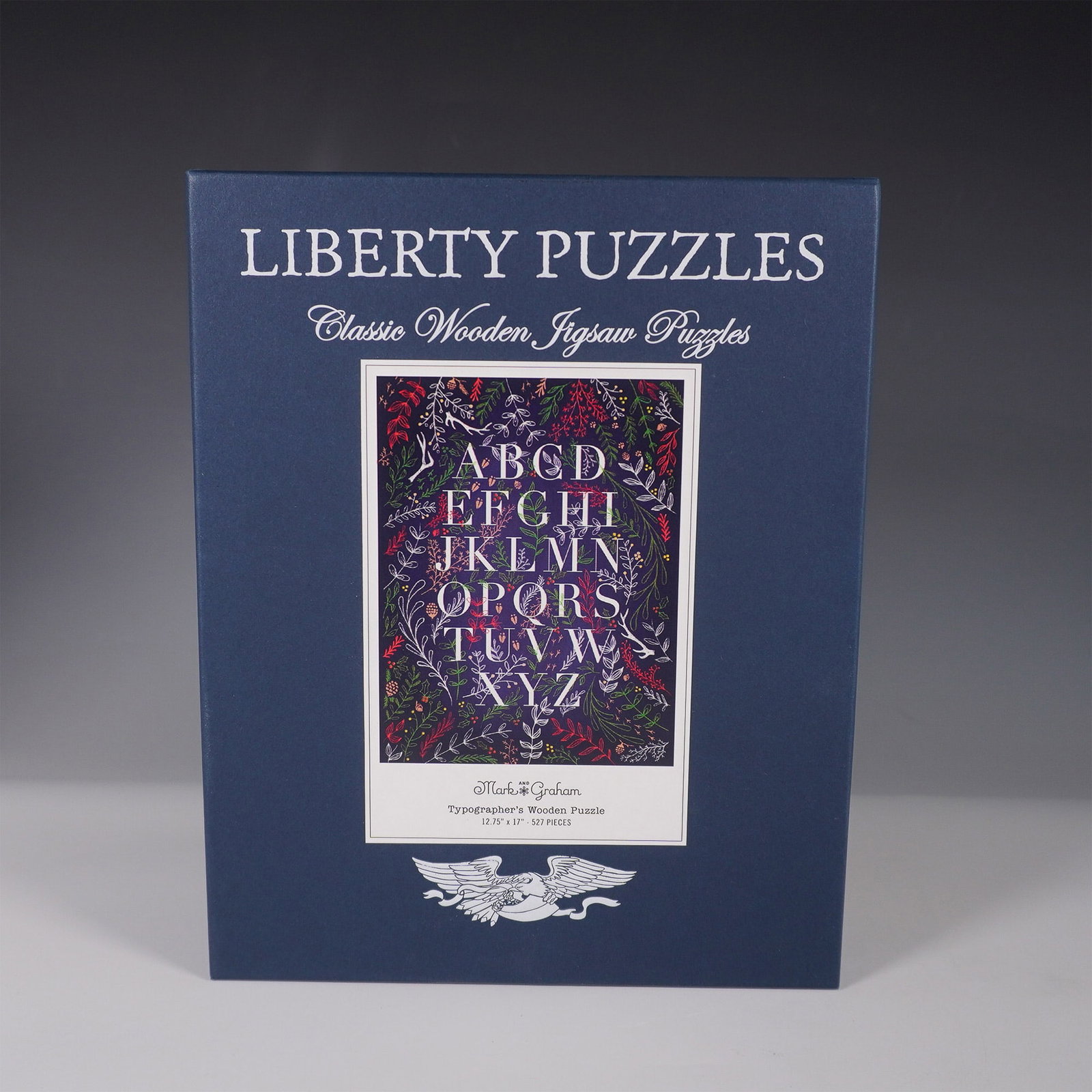 Liberty Puzzles Typographer's Wooden Puzzle: A finely crafted wooden jigsaw puzzle by Liberty Puzzles, featuring the Typographer's design by Mark Graham. This intricate puzzle showcases a beautifully detailed alphabet composition surrounded by d