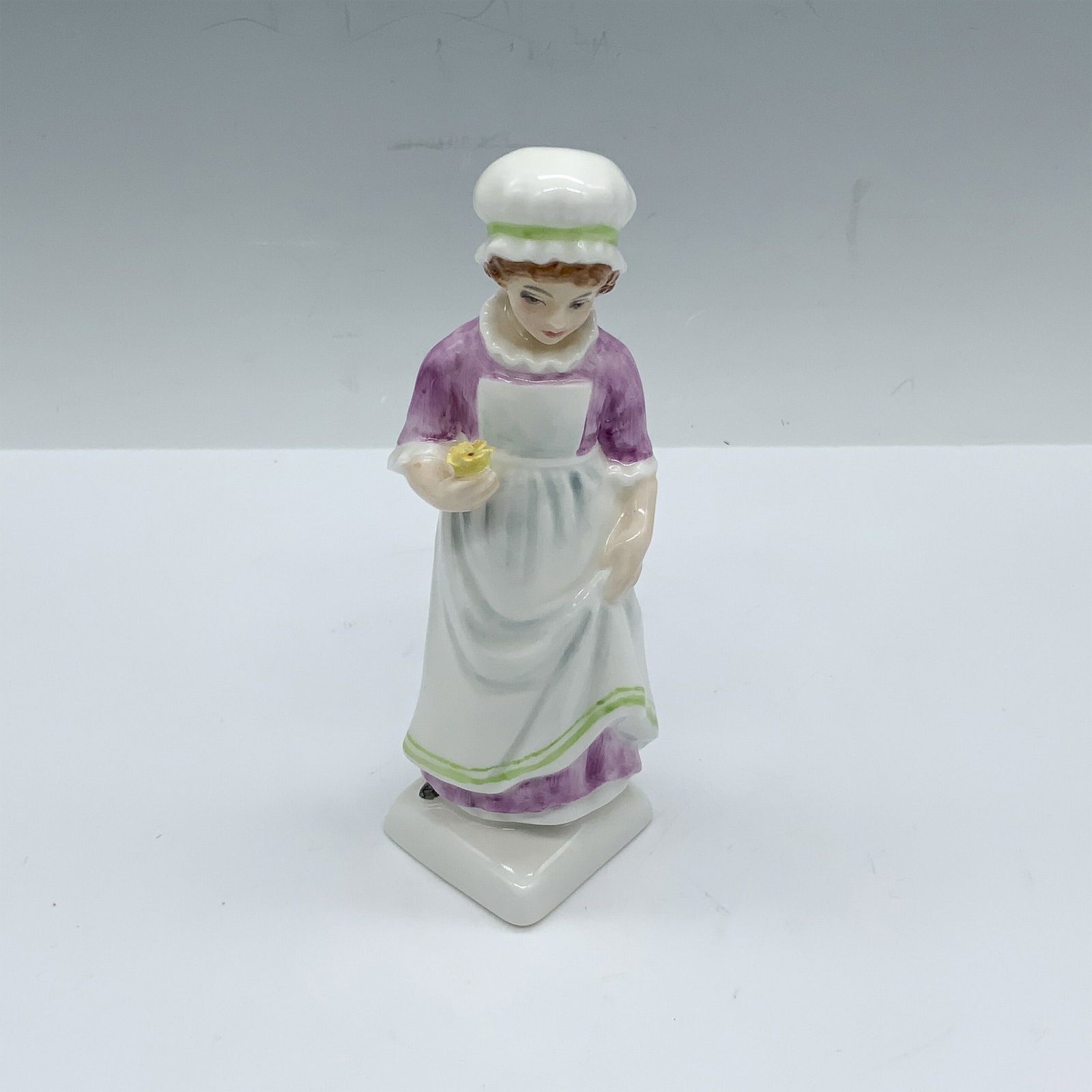 Beth HN2870 - Royal Doulton Figurine: This young girl with a yellow flower figure from the Kate Greenaway Collection is based of one of Kate's books named Under The Window which contains idyllic verses concerning children who endlessly ga