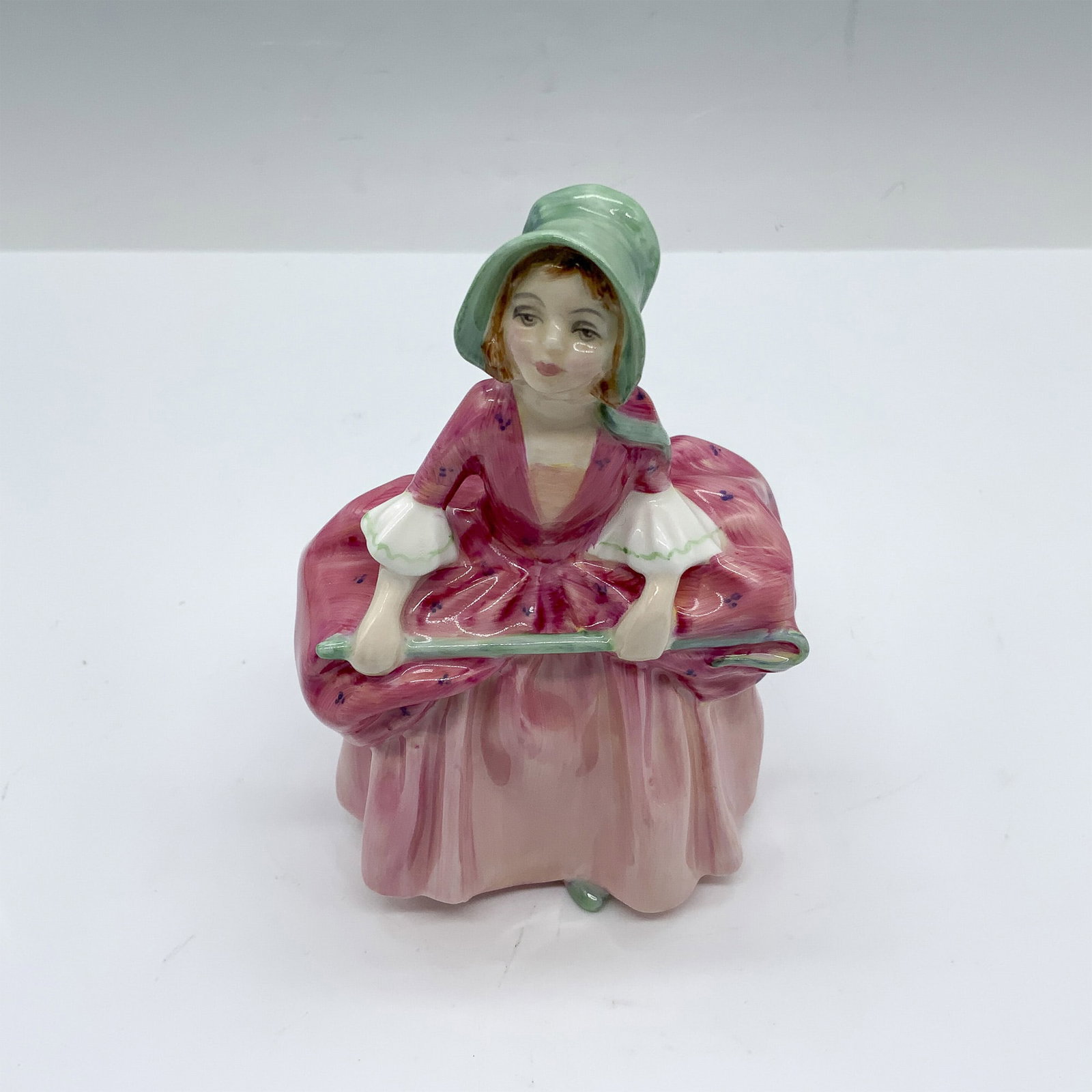 Bo Peep HN1811 - Royal Doulton Figurine: This figure looks adorable in her soft pink dress that is delicately detailed with small flowers a white ruffled at the cuff as well as a light green bonnet with strings dangling over her shoulders. S