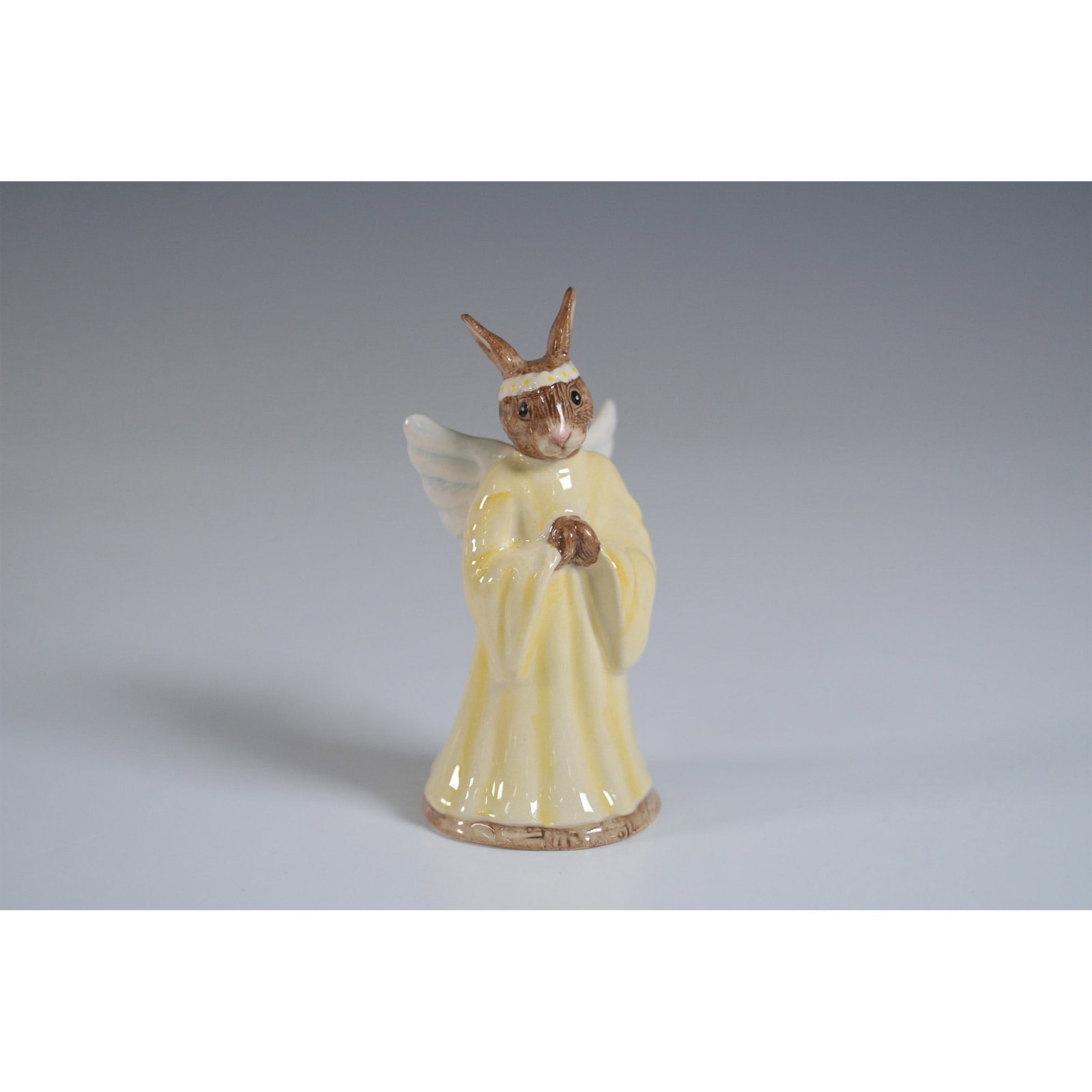 Angel Bunnykins DB196 - Royal Doulton Bunnykins: Charming Royal Doulton Bunnykins figurine titled Angel Bunnykins, model DB196. This porcelain figurine features a delightful bunny dressed as an angel, wearing a soft yellow robe with detailed wings a