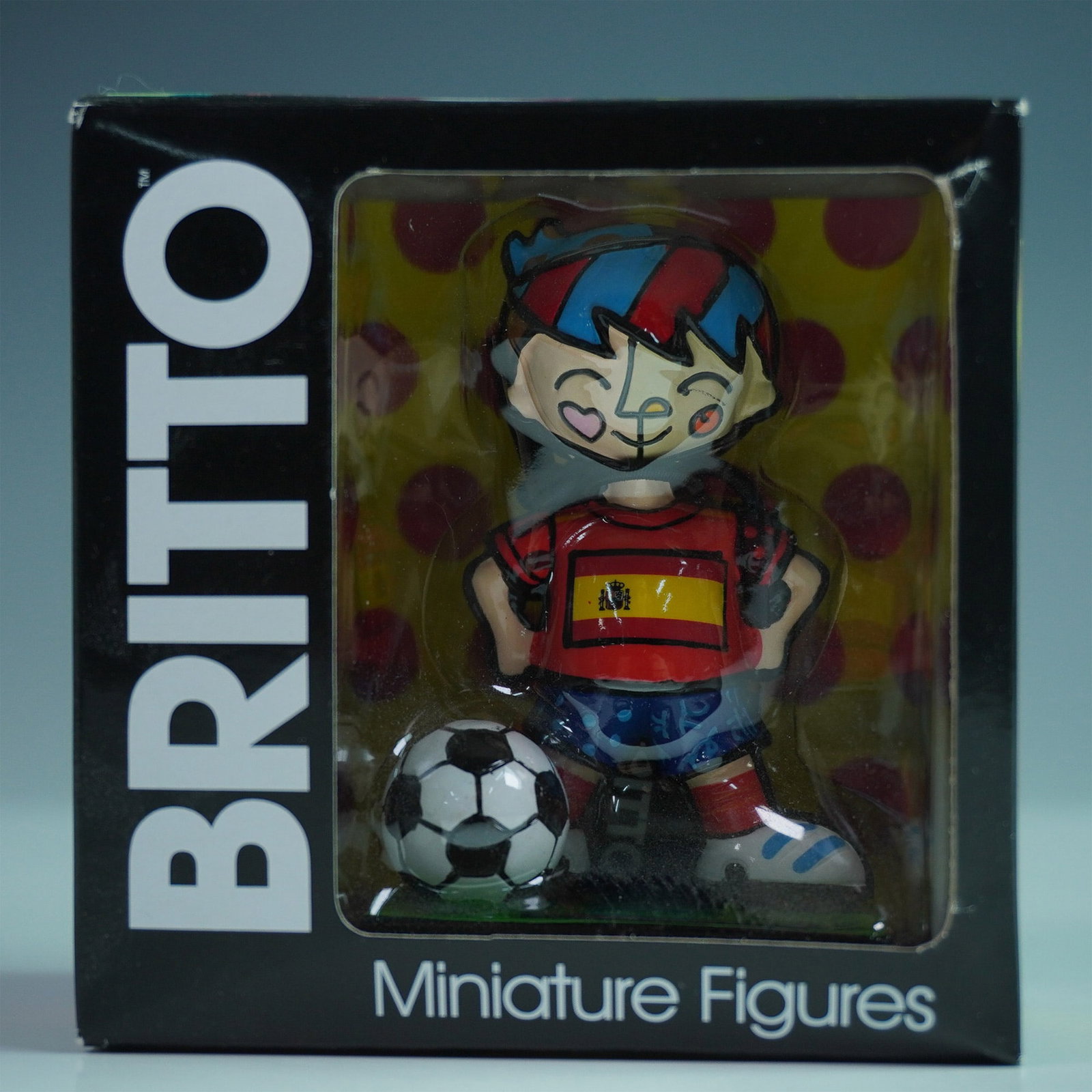 Romero Britto (Brazilian, b. 1963) Mini Figurine, Spain Soccer: Collectible stone resin figure representing a Spain soccer player, part of the World Cup mini figure series. The figure is characterized by Britto's signature graphic style, incorporating segmented co