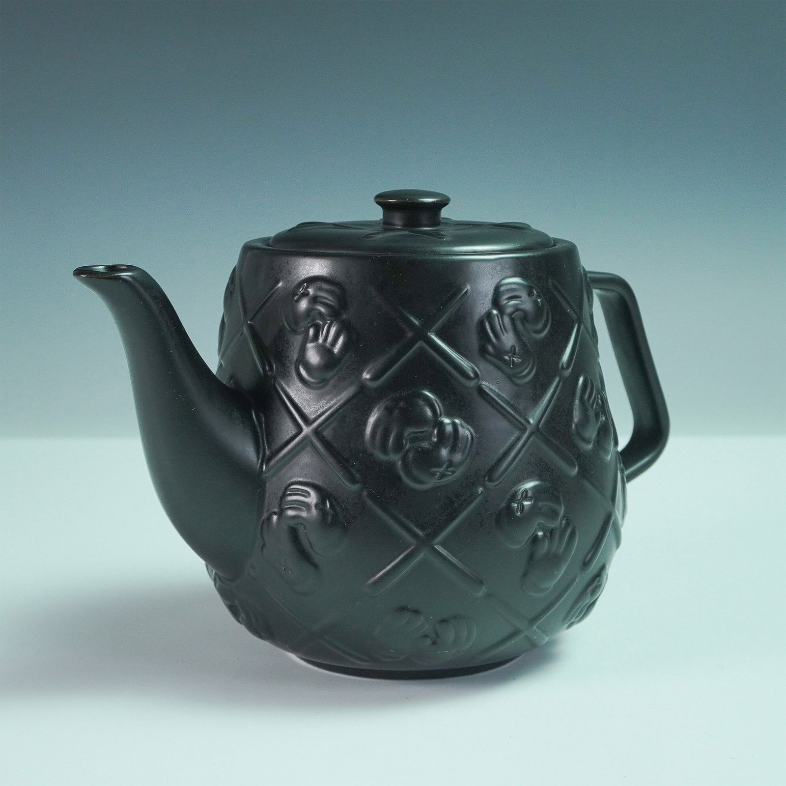KAWS Black Ceramic Teapot: A KAWS black ceramic teapot featuring the artist's signature Companion face motif in a quilted pattern. After his first Teapot sold out in a flash, artist Brian Donnelly (KAWS) is back with an all-bla