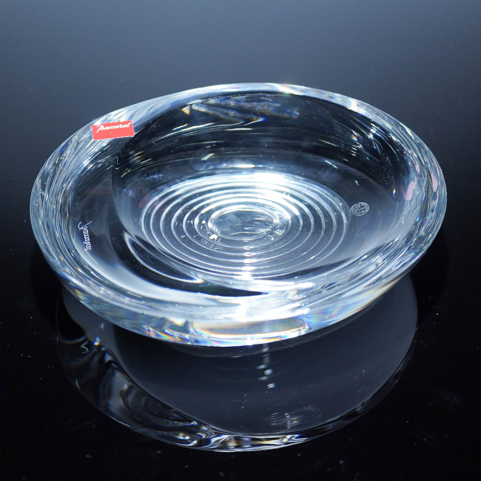 Baccarat Crystal Hypnos Dish: Clear crystal Hypnos dish by Baccarat, featuring a minimalist round form with a distinctive concentric circle pattern at the base. The design evokes a hypnotic ripple effect, true to its name. Etched 