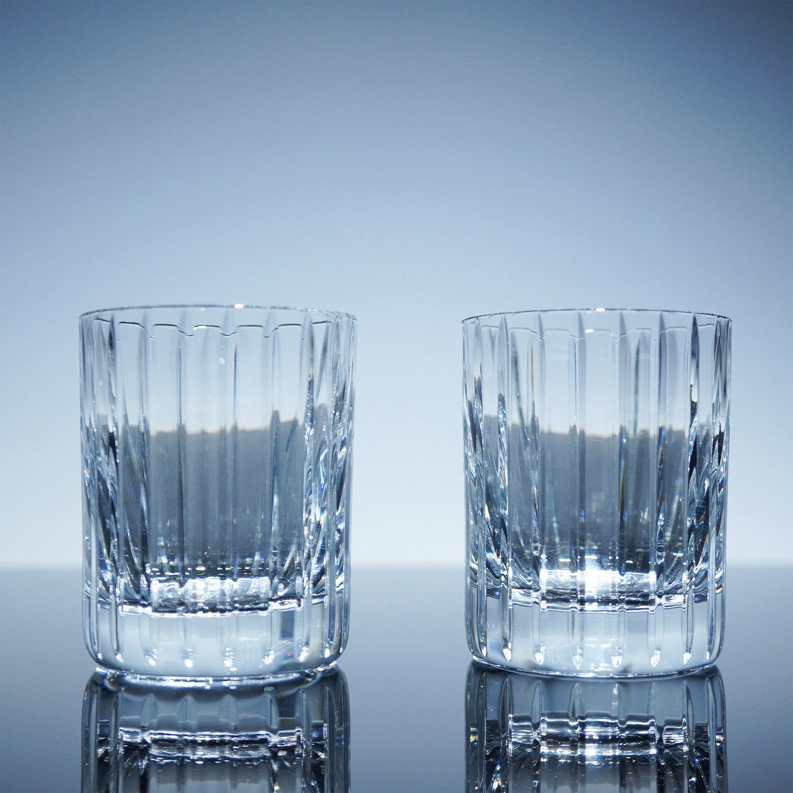 Pair of Baccarat Crystal Double Shot Glasses, Harmonie: This elegant pair of Baccarat Harmonie double shot glasses features a timeless vertical cut pattern that enhances the clarity and brilliance of the crystal. Designed for refined drinking experiences, 