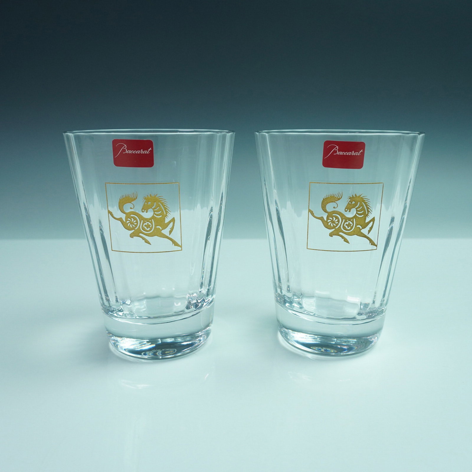 Set of 2 Baccarat Crystal Tumblers, Zodiac Horse Design: A striking pair of Baccarat crystal tumblers featuring the limited edition Zodiac Horse motif in gilded detail. Each tumbler is beautifully cut with signature Baccarat brilliance and adorned with the 
