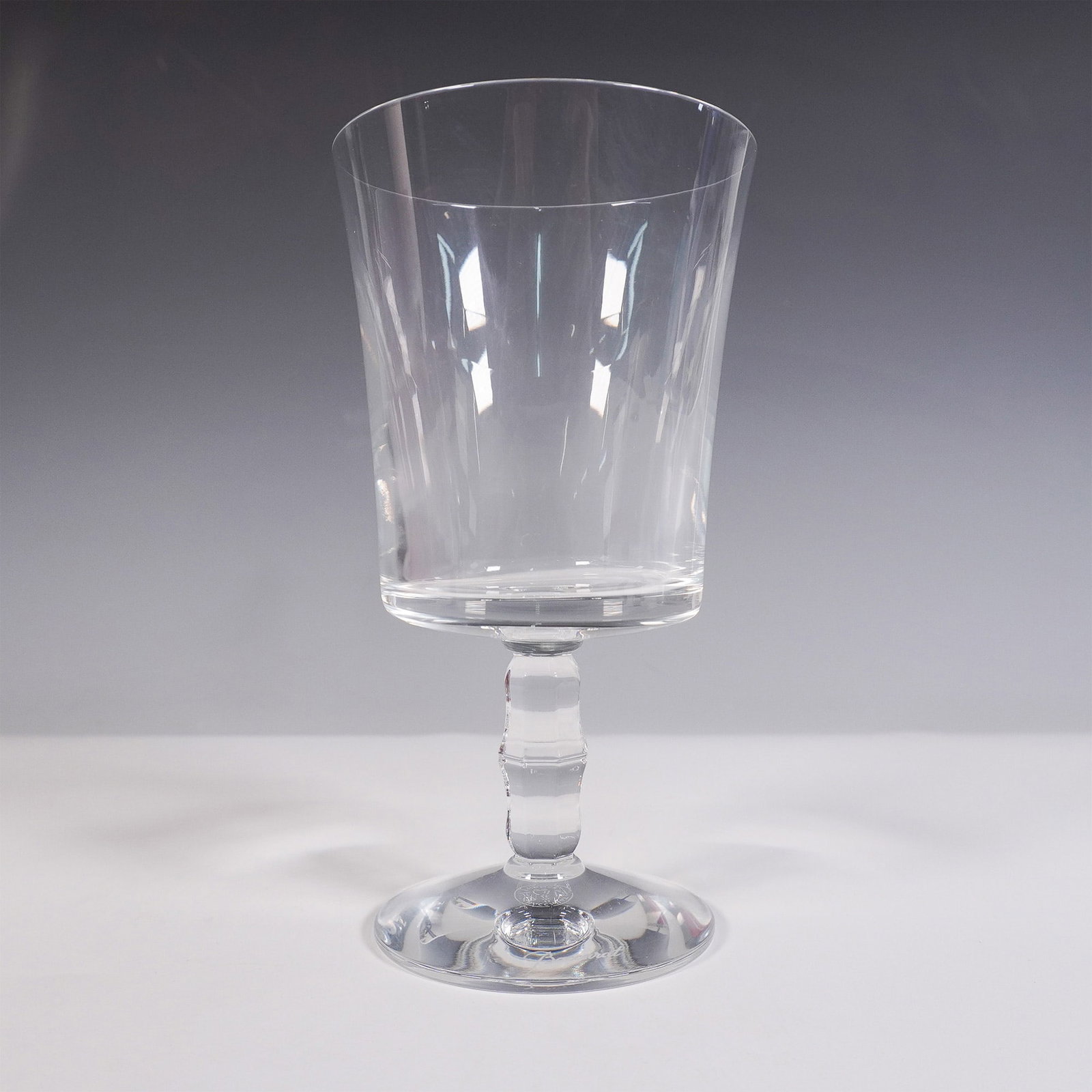 Baccarat Crystal Wine Glass, Embassy: A clear crystal wine glass featuring a plain, squarish bowl and a faceted wafer stem. The base is etched with the Baccarat logo and factory hallmark. This item is presented in its original red Baccara