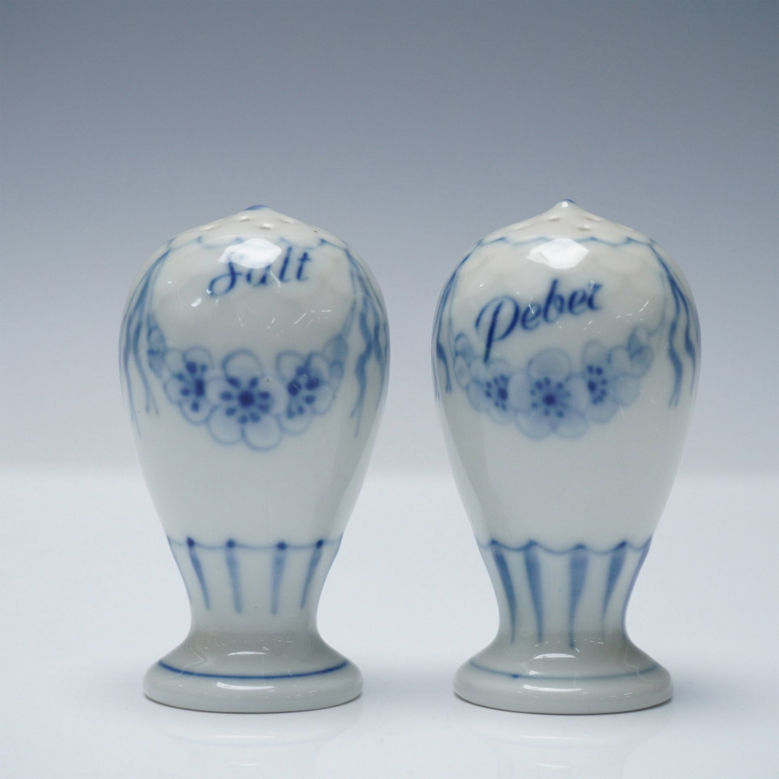 2pc Bing & Grondahl Blue Fluted Salt & Pepper Shakers: A charming pair of Bing & Grondahl porcelain salt and pepper shakers in the classic Blue Fluted design. Each shaker features delicate hand-painted floral motifs in cobalt blue with Danish script label