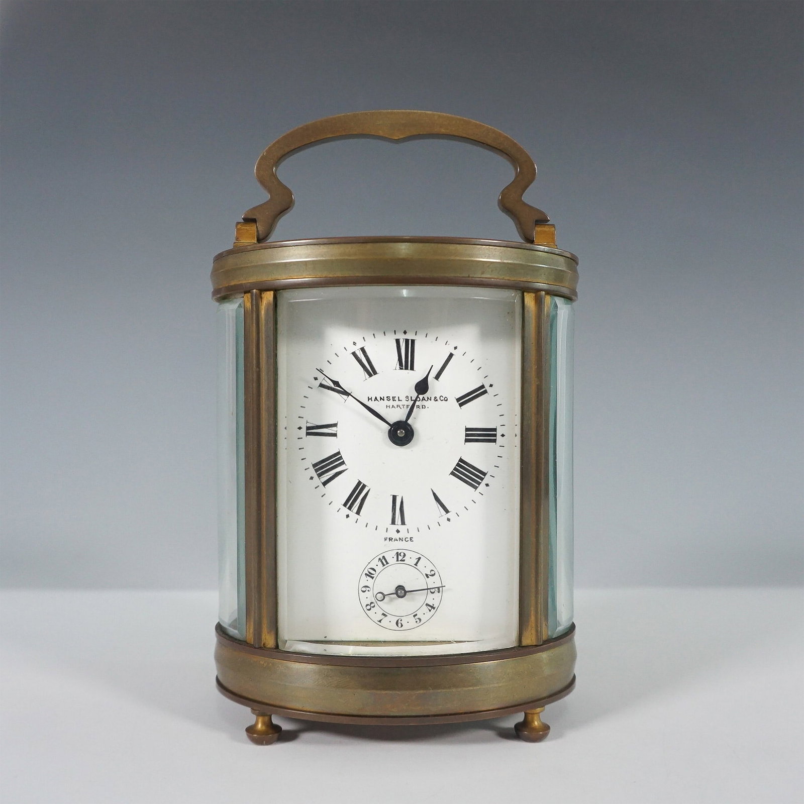French Brass and Glass Carriage Clock by Hansel Sloan & Co.: Elegant antique French brass and glass carriage clock, signed by Hansel Sloan & Co. on the enamel dial. Featuring a classic Roman numeral face with a subsidiary seconds dial and an eight-day movement.