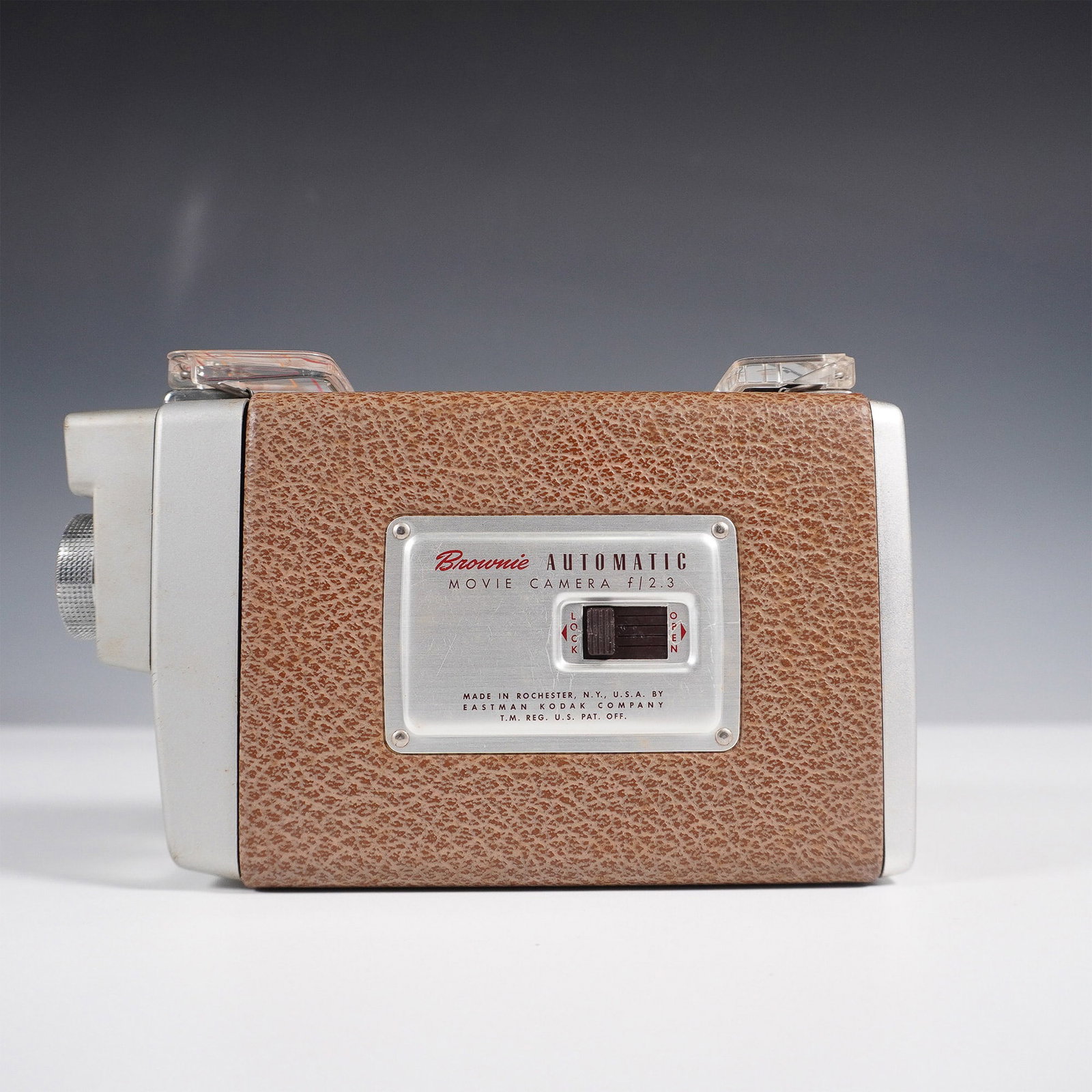 Kodak Brownie Automatic Movie Camera f/2.3: This Kodak Brownie Automatic Movie Camera f/2.3, produced by Eastman Kodak Co. in Rochester, NY, features a textured brown body with silver-tone metal accents and a built-in electric eye exposure cont