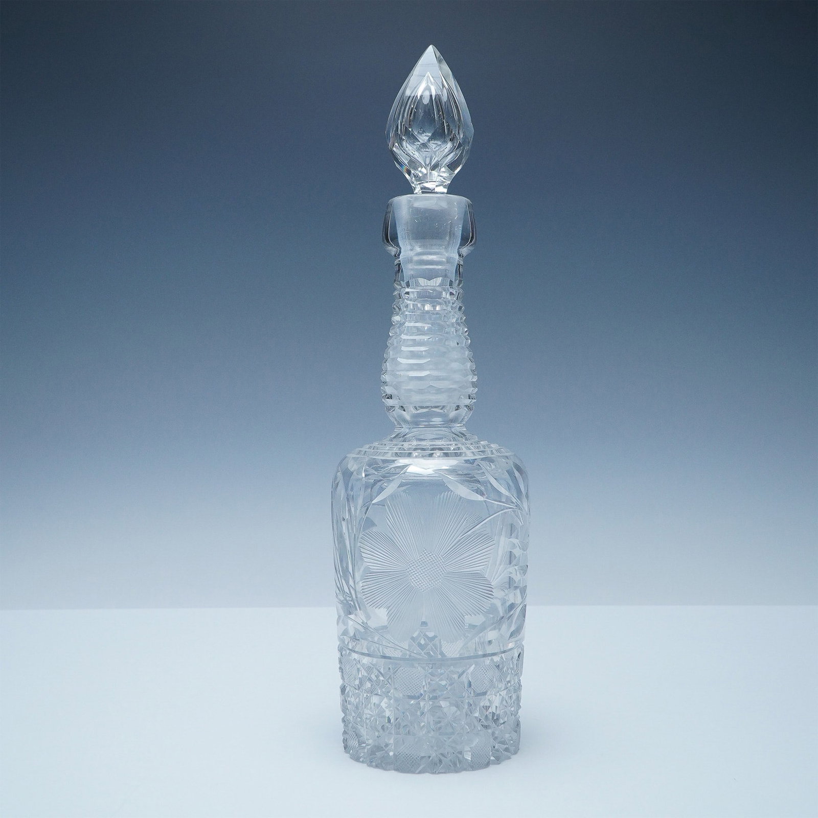 Vintage Clear Glass Decanter with Floral Motif: Elegant vintage clear glass decanter featuring an intricately cut floral motif on both the front and back. The detailed design adds a touch of sophistication, complemented by a matching stopper with f