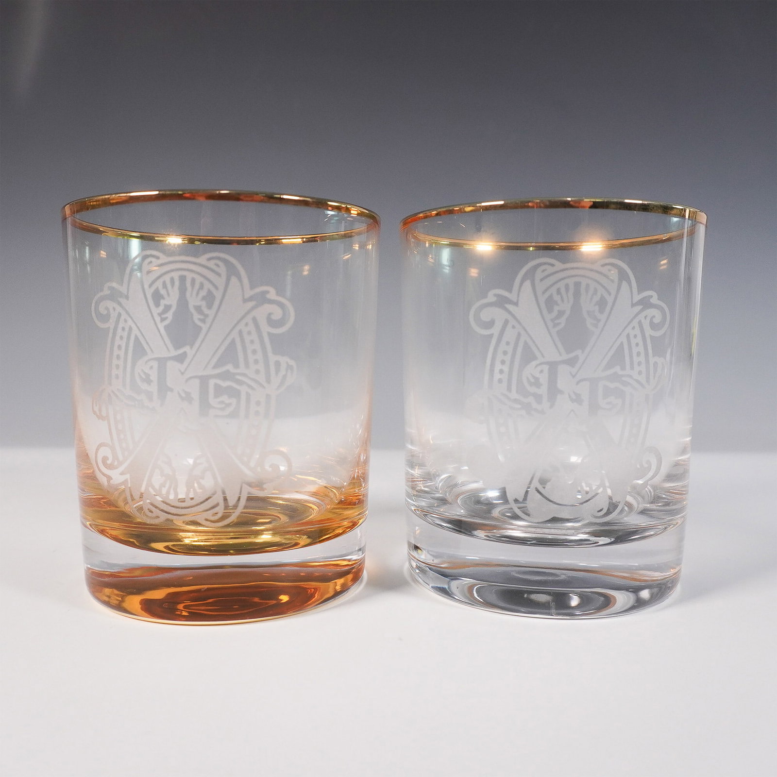 Pair of Arturo Fuente Whiskey Glasses: Arturo Fuente whiskey glass set featuring two premium rocks glasses in amber and clear finishes. Each glass is etched with the iconic Arturo Fuente "AF" insignia and adorned with a gold rim. The set i