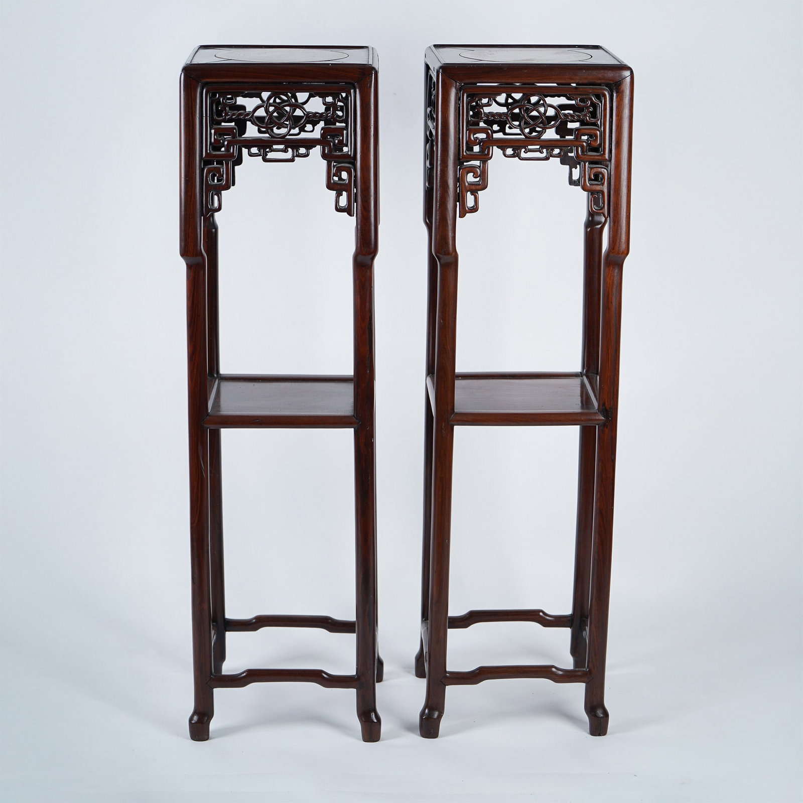 2pc Chinese Hardwood Pedestals, Marble Inlaid Tops: A pair of Chinese hardwood pedestals featuring intricate reticulated carvings and marble-inlaid tops, likely crafted from rosewood. These tall and elegant stands reflect Ming Dynasty-inspired aestheti