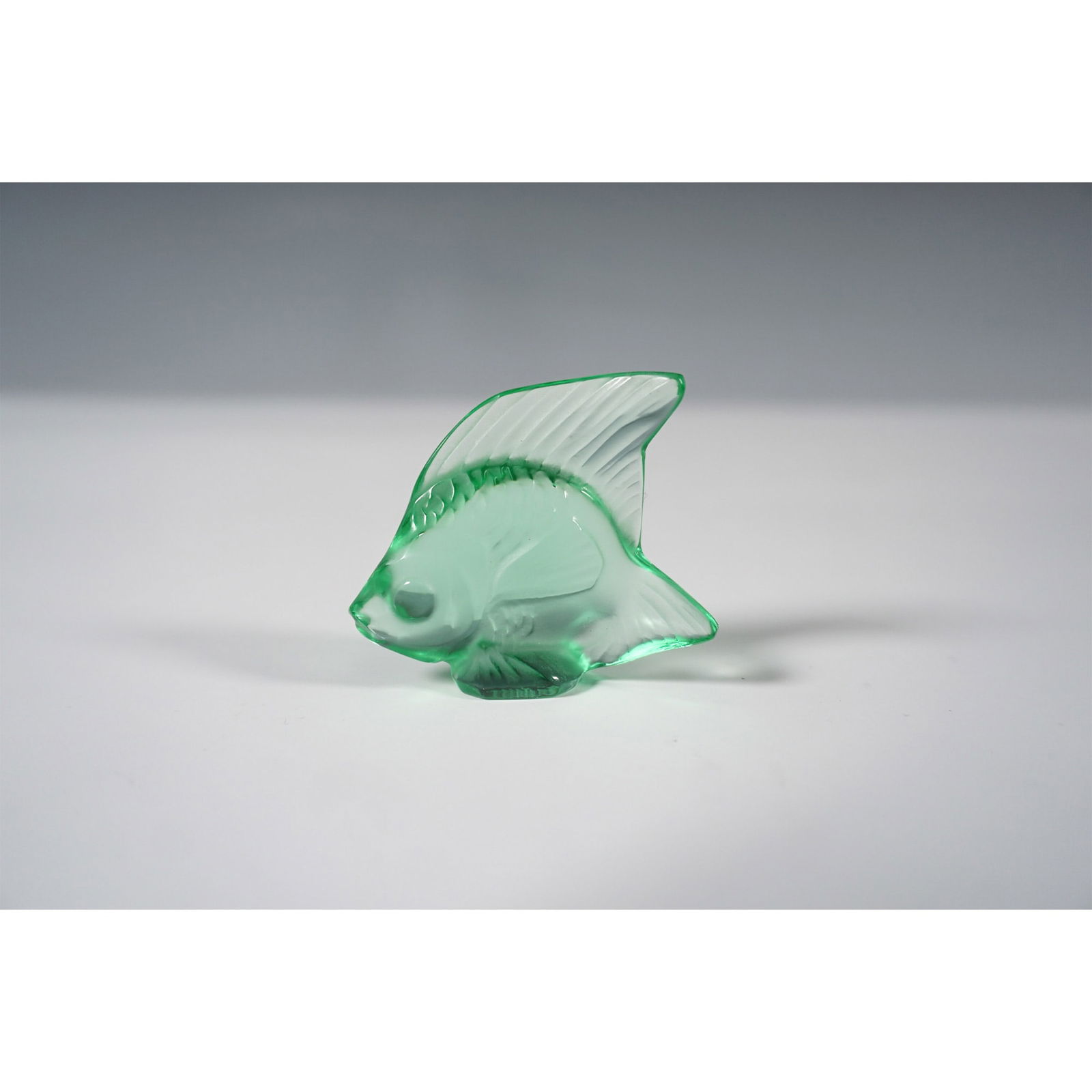 Lalique Crystal Emerald Green Fish Figurine: This figurine showcases the iconic fish design created by Rene Lalique in 1913, featuring a delicate interplay of frosted and polished crystal. Rendered in a striking emerald green hue, this piece hig