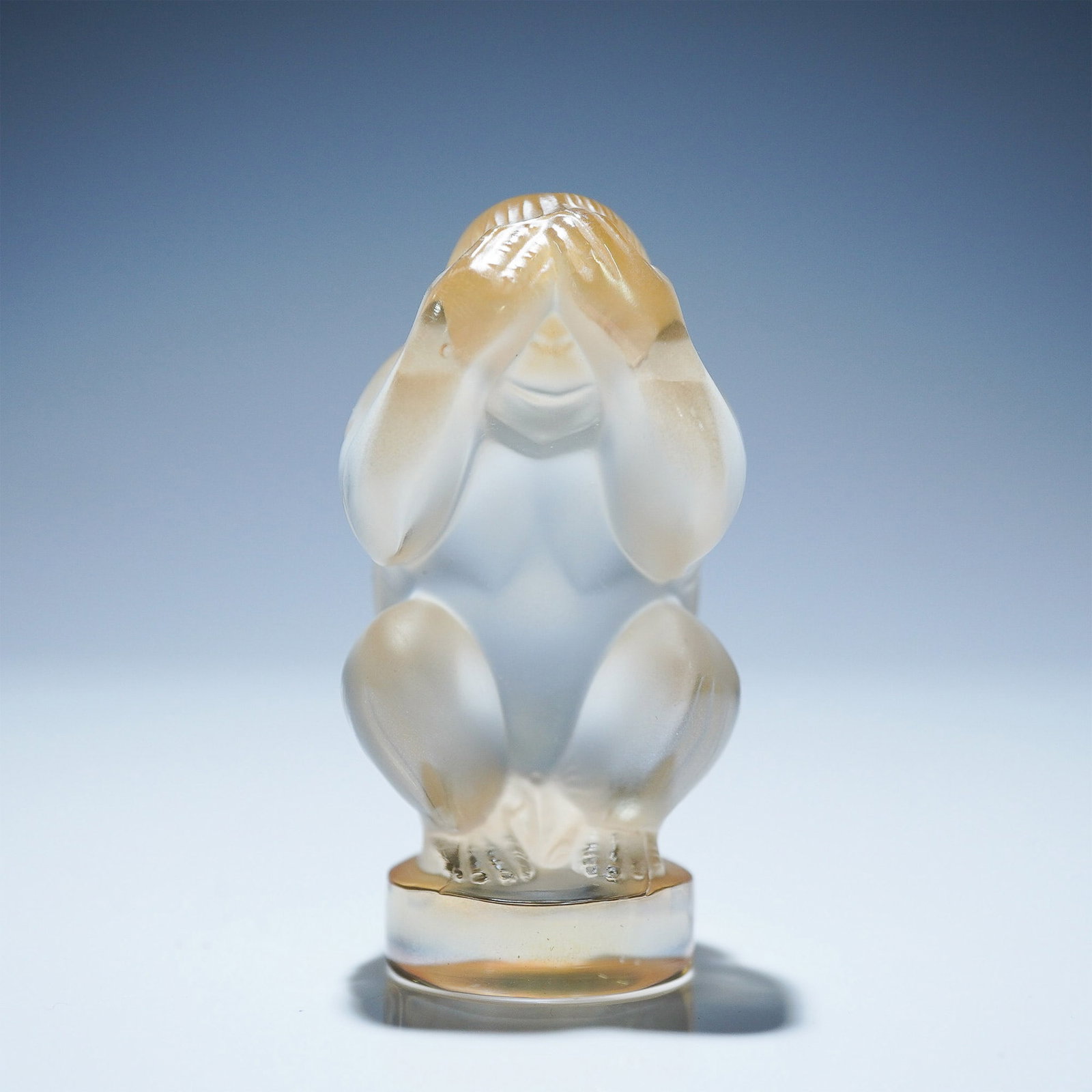 Lalique Crystal Figurine, Wise Monkey See No Evil: This finely rendered Lalique crystal figurine captures the timeless image of the “See No Evil” monkey, seated with hands gently covering its eyes. Executed in frosted and polished crystal, the pie