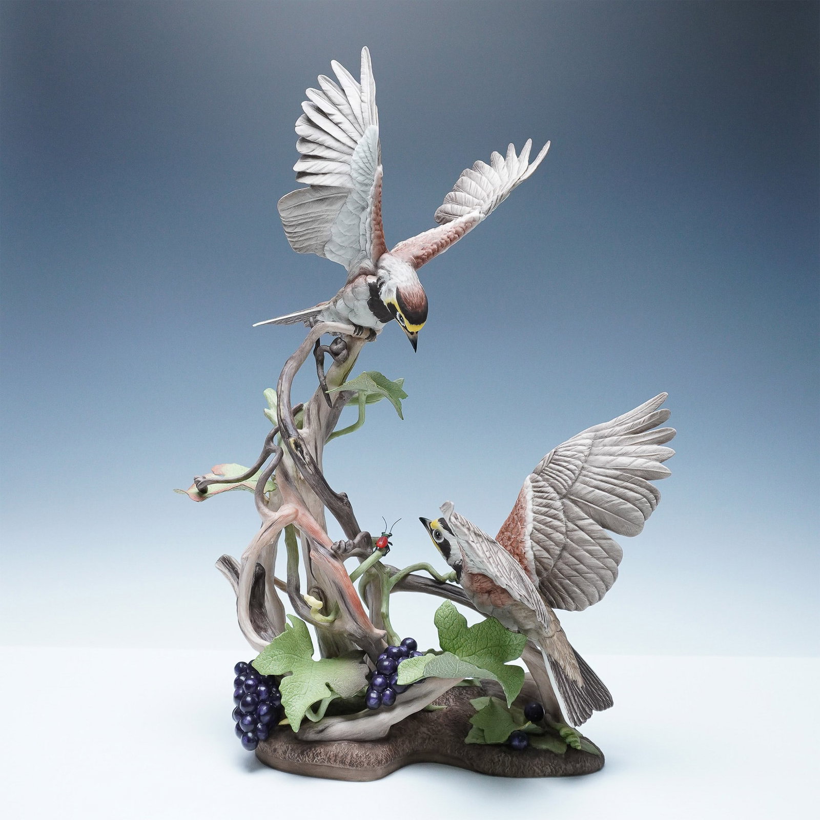 Boehm Limited Edition Horned Lark Porcelain Sculpture: A stunning Boehm limited edition bone porcelain sculpture depicting a pair of horned larks in a naturalistic setting, surrounded by intertwined branches, grapevines, and a ladybug perched on a vine. T