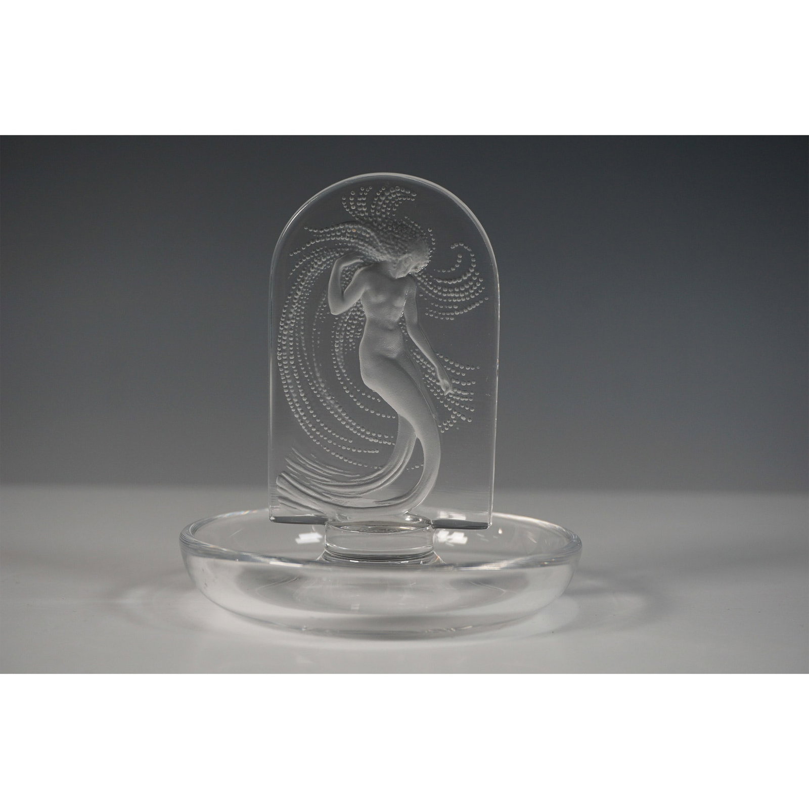 Lalique Inspired Naiade Round Pin Tray: A pin tray in the style of Lalique, featuring an elegant frosted glass Naiade figure rising from a round dish. The Naiade, a water nymph, is gracefully posed with flowing hair accentuated by intricate