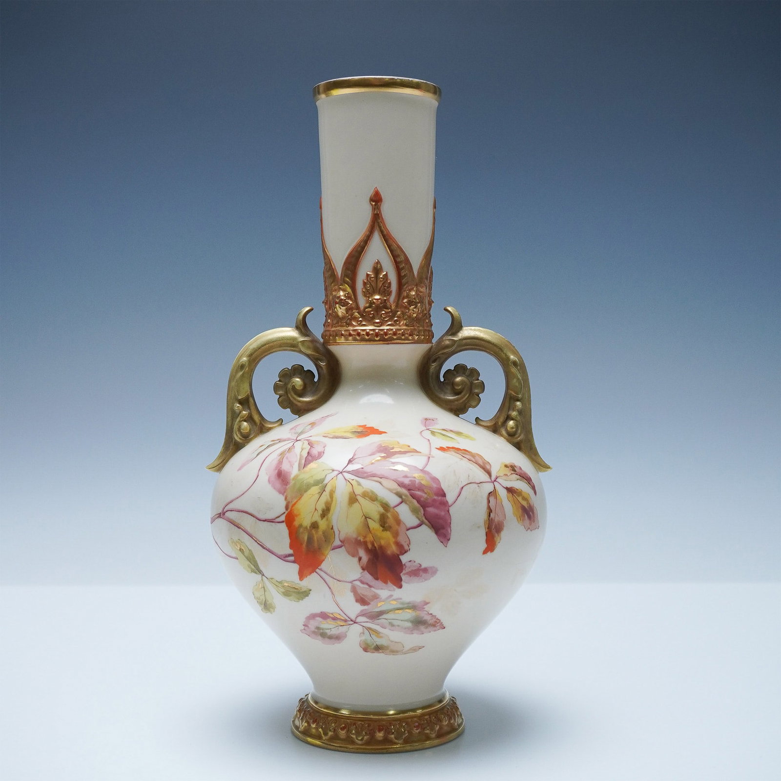 Royal Worcester Patent Metallic Floral Vase, 1075: Porcelain vase features a Patent Metallic finish and is decorated with a floral design. The vase has a rounded body with a slender neck and is adorned with elaborate gilt accents. It includes two orna