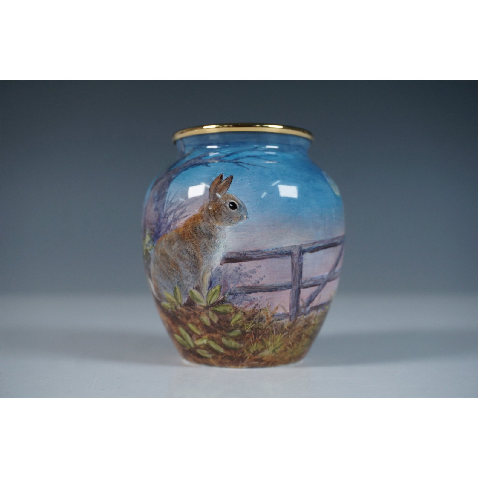 Moorcroft Enamel by Terry Halloran Vase, Rabbits: A Moorcroft Enamel mini vase designed by Terry Halloran. This limited-edition piece features an intricately detailed moonlit woodland scene, depicting two rabbits along a rustic fence amidst lush foli