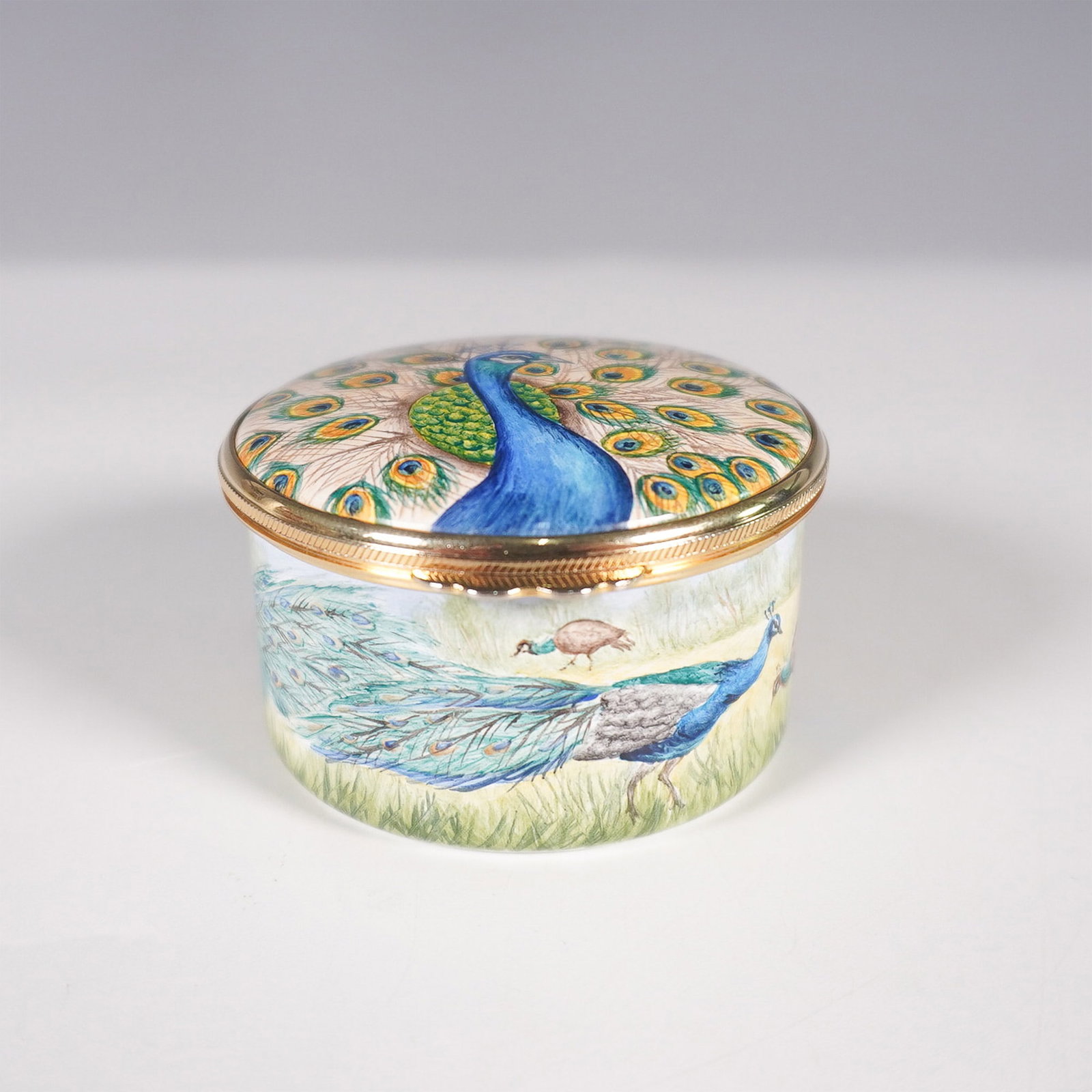 Moorcroft Peacock Enamel Box - Trial Piece: A Moorcroft enamel box featuring an exquisitely hand-painted peacock design, marked as a trial piece on the base. The lid showcases a striking portrait of a peacock with its feathers fully fanned, whi