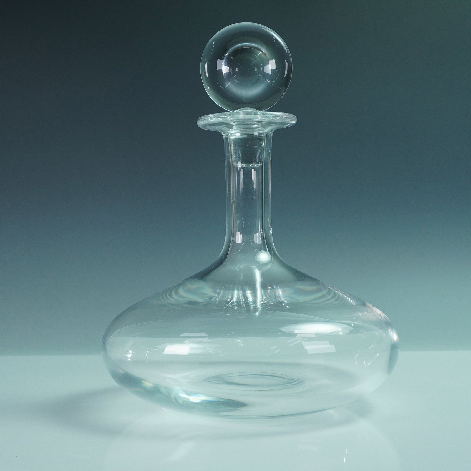 Baccarat Crystal Ship's Decanter: A refined Baccarat crystal ship's decanter featuring a wide, flat base designed for stability, a gracefully tapered neck, and a striking spherical stopper. This design, originally intended to prevent 