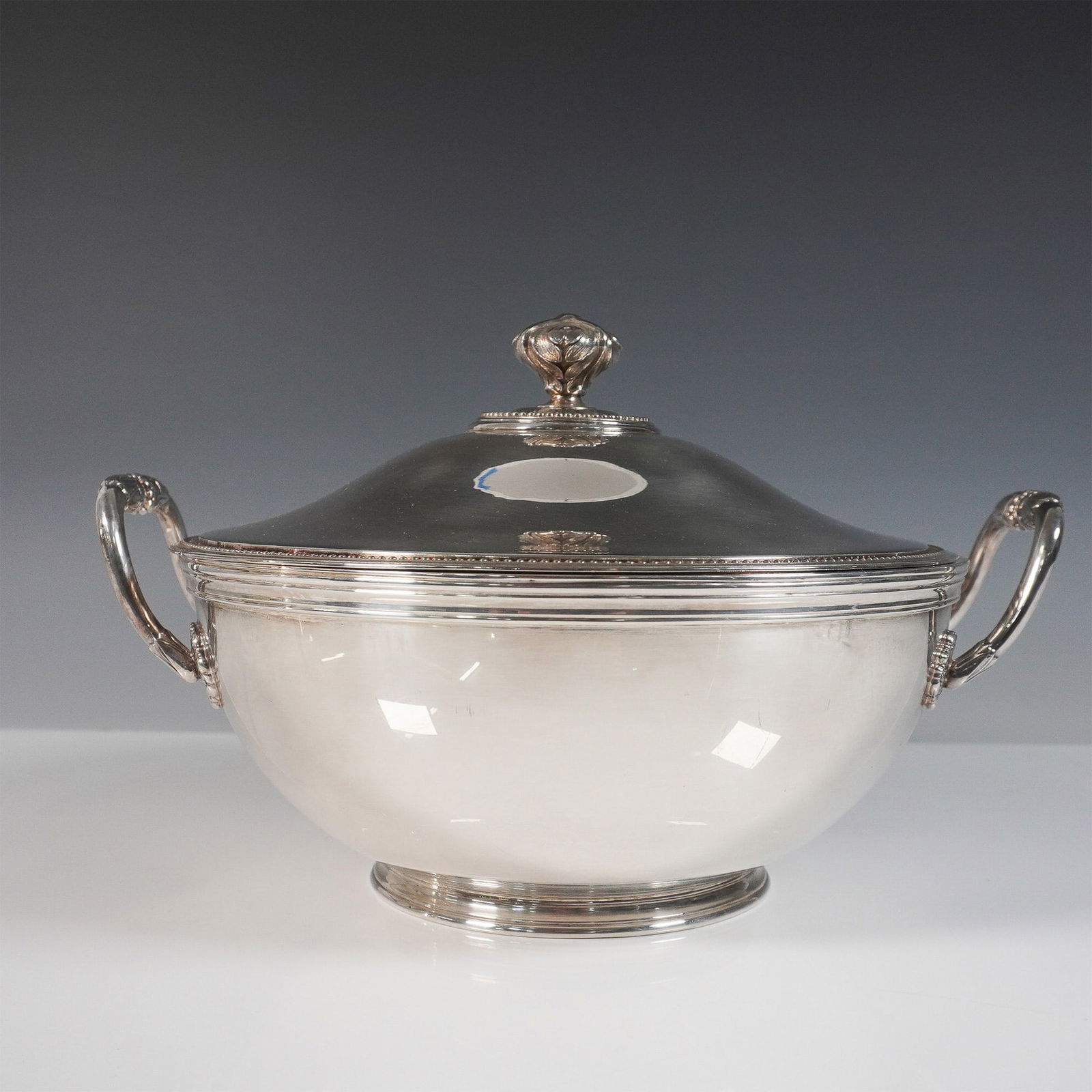 Christofle Silver Plated Covered Tureen: Elegant Christofle silver-plated covered tureen featuring a classic design with a gently rounded body, ornate dual handles, and a domed lid topped with a decorative finial. This refined serving piece