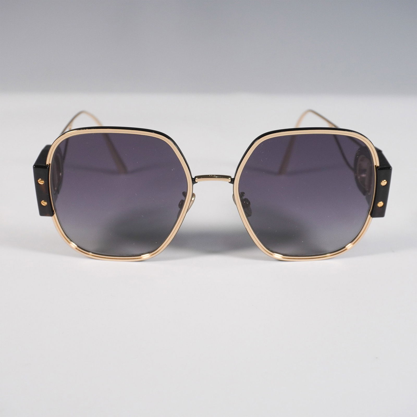 Christian Dior 30Montaigne S5U Sunglasses: A striking pair of Christian Dior 30Montaigne S5U sunglasses featuring a bold geometric gold-tone metal frame with black acetate temple accents. These oversized square sunglasses offer a modern and so