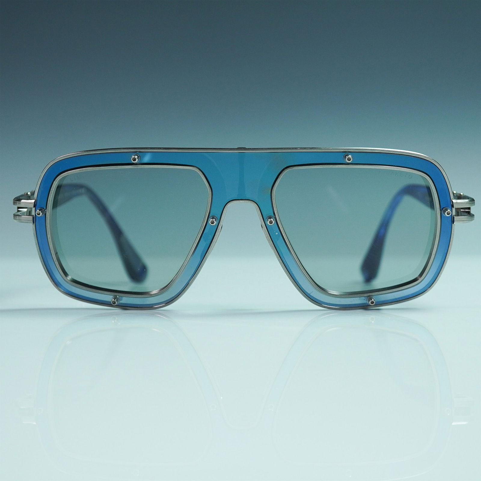 Dita Raketo Limited Edition Sunglasses, Model DTS422 A 03: Sleek and bold, these limited edition Dita Raketo sunglasses feature a modern geometric aviator silhouette with a striking blue and titanium frame. Crafted in Japan, this model (DTS422-A-03) showcases