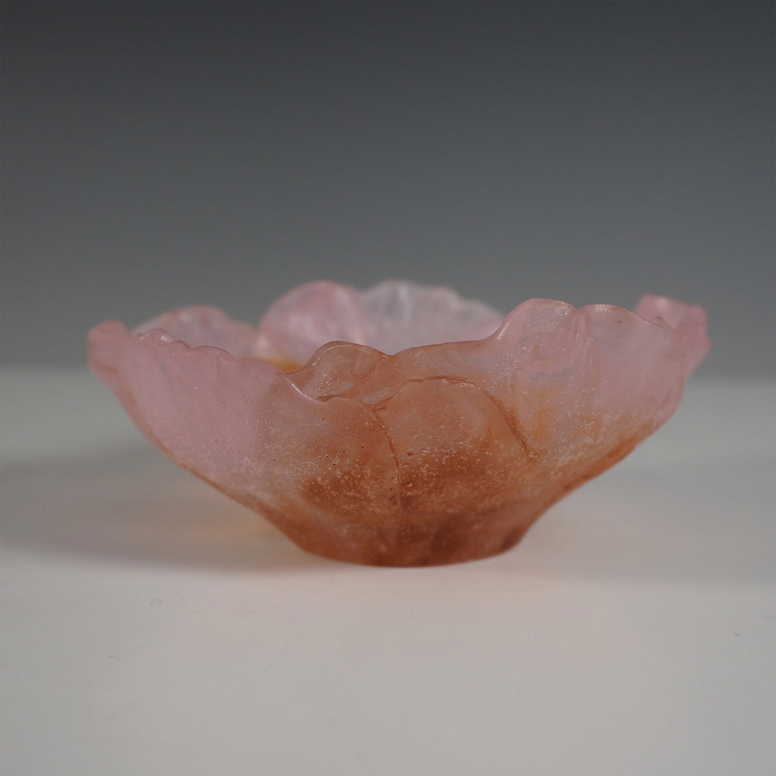 Daum France Pate de Verre Pink and Amber Floral Bowl: A stunning Daum France pate de verre glass bowl, delicately crafted in the form of a blooming flower. The translucent glass exhibits a graceful gradient of pink and amber hues, with a frosted texture