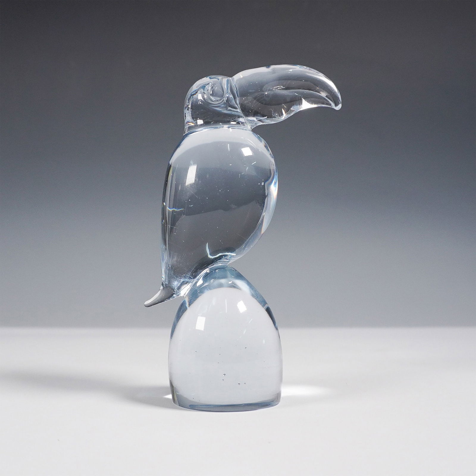 Murano Export Art Glass Toucan Sculpture, Signed: A stunning hand-blown export art glass sculpture of a toucan, featuring a sleek and modern design with a light blue tint. The piece is elegantly crafted with smooth curves and a minimalist aesthetic,