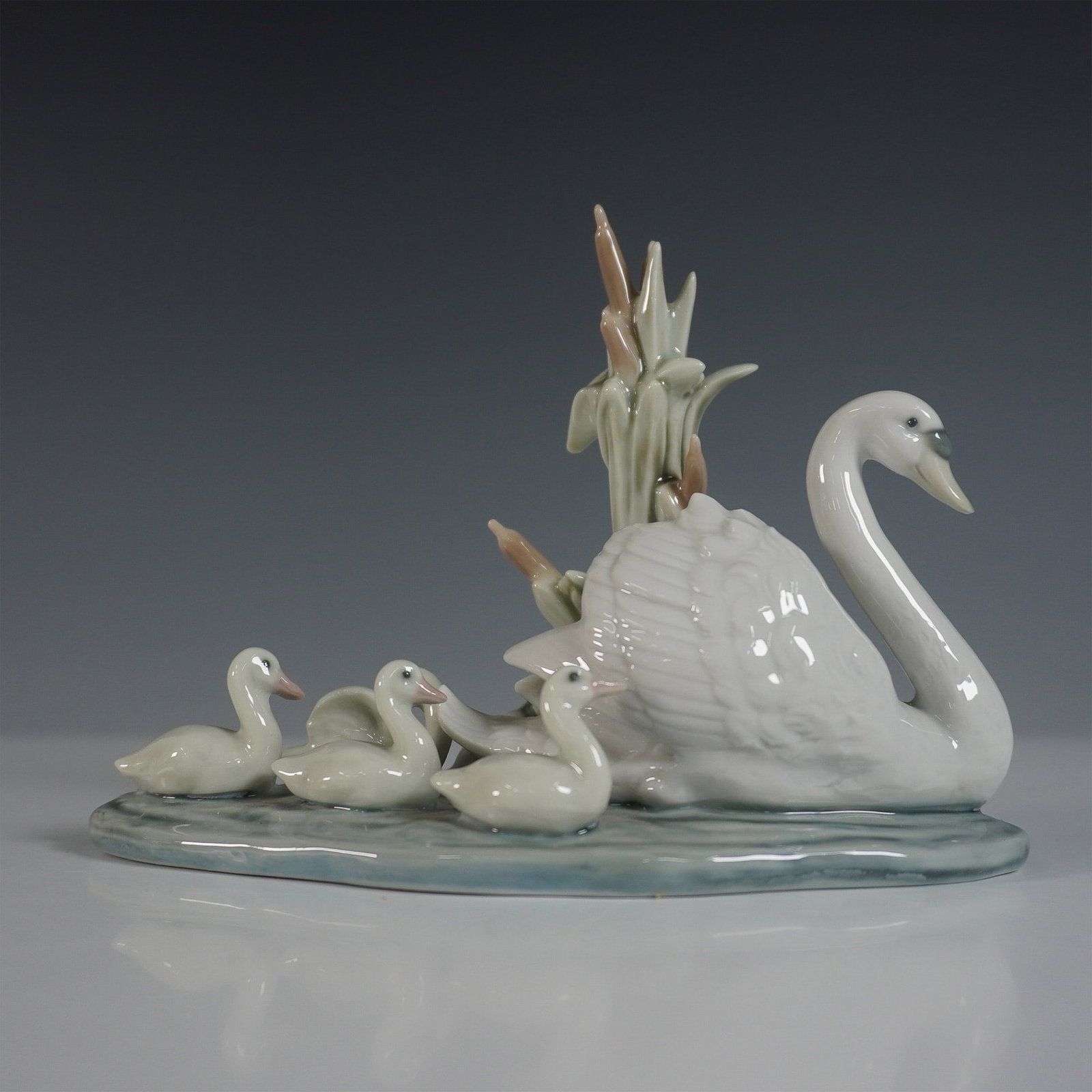 Lladro Follow Me Porcelain Figurine 01005722: A graceful Lladro porcelain figurine titled Follow Me (01005722), depicting a mother swan leading her adorable cygnets across a tranquil pond. This beautifully sculpted piece features lifelike detaili