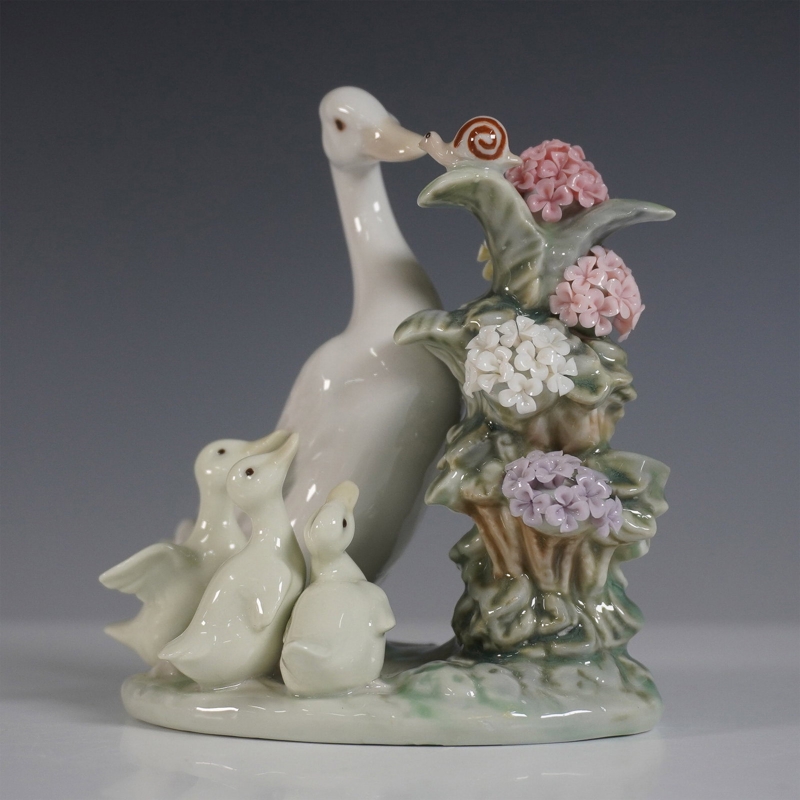 Lladro Porcelain Figurine, How Do you Do 01001439: Charming Lladro porcelain figurine titled How Do You Do, model number 01001439. Designed with exquisite detail, this piece features a mother duck and her ducklings encountering a friendly snail among 