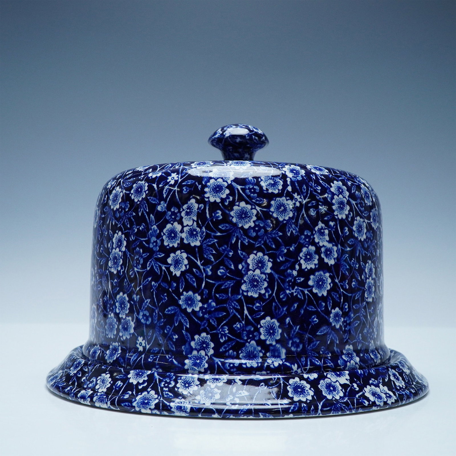 Burleigh Calico Blue Staffordshire Covered Cheese Dome: Classic English craftsmanship is on display with this Burleigh Calico Blue covered cheese dome, a fine example of traditional Staffordshire pottery. Featuring a rich cobalt blue floral chintz pattern 