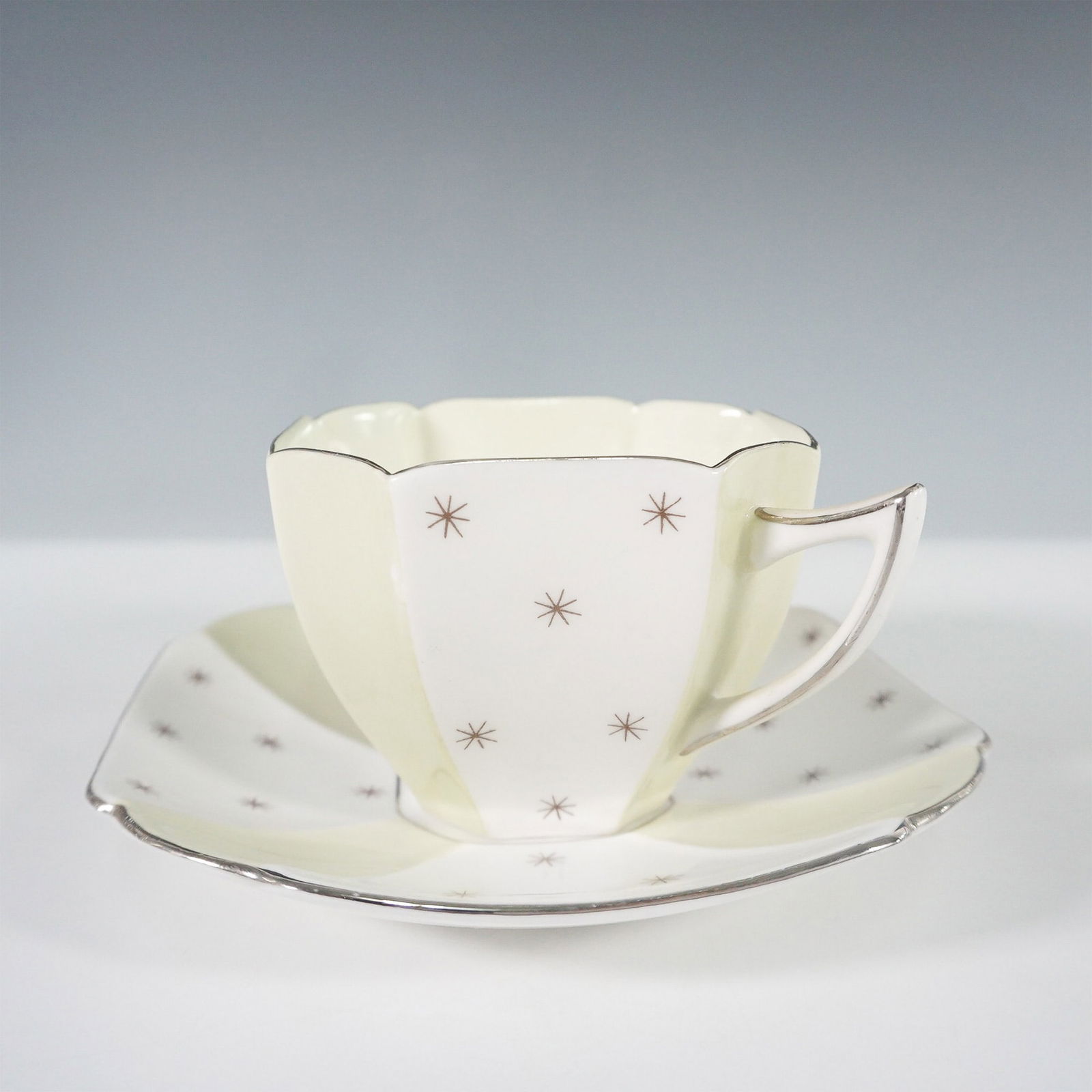 2pc Shelley England Pole Star ? Cup and Saucer: Shelley England Pole Star duo set, featuring a striking Art Deco cup and saucer. This geometric design showcases a cream and pale yellow color scheme accented with delicate brown starbursts and silver