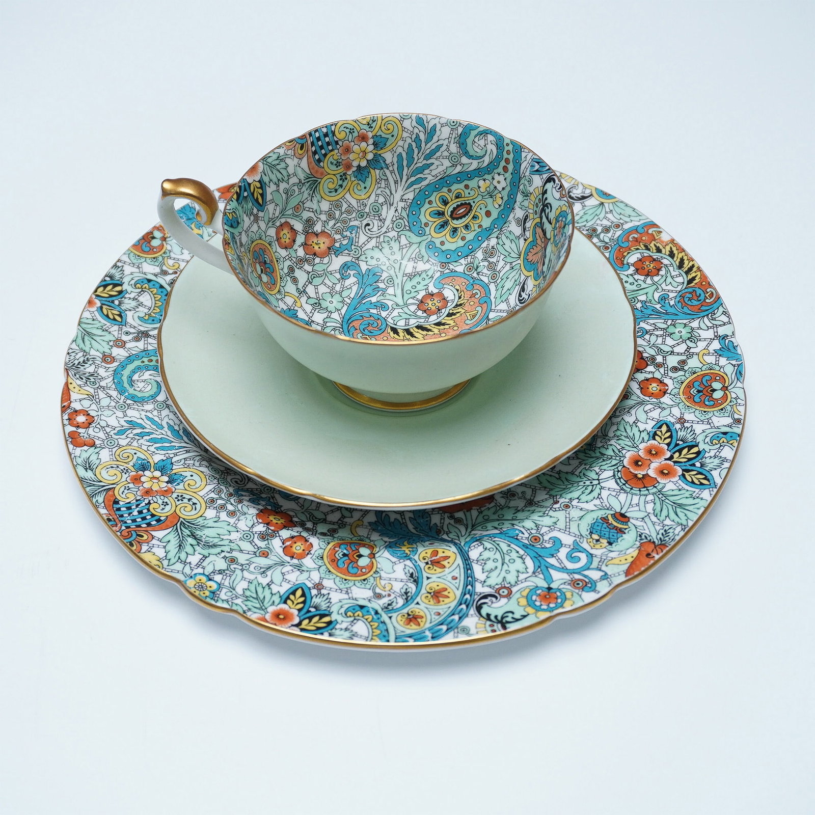 3pc Shelley Green Paisley Trio Tea Set: A three-piece Shelley fine bone china tea set featuring a green paisley chintz pattern. The set includes a teacup, saucer, and tea plate. Each piece is adorned with intricate chintz floral motifs and 