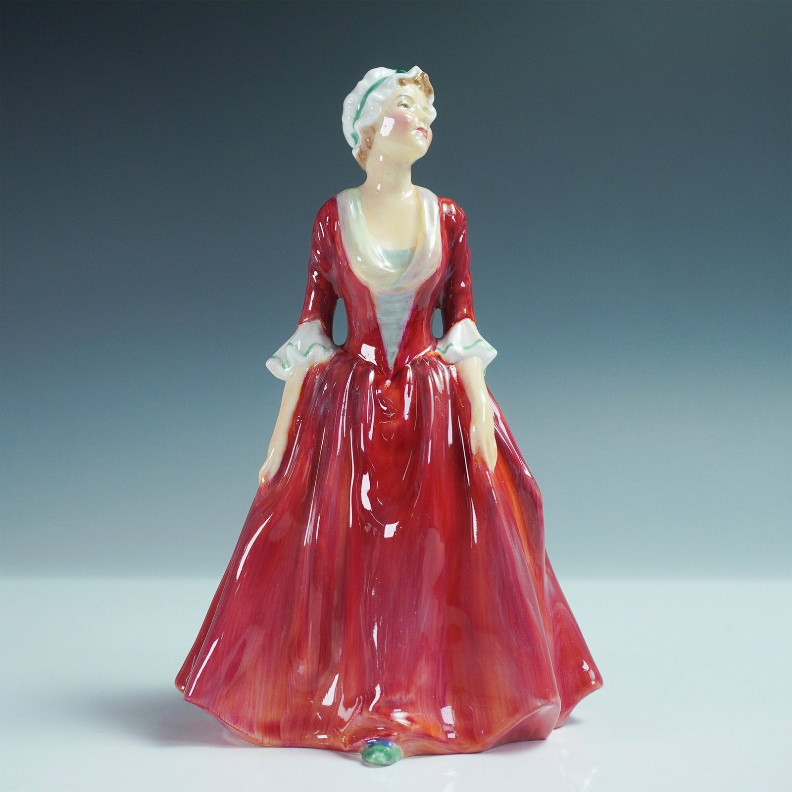 Royal Doulton Figurine, Gwynneth HN1980: Royal Doulton figurine Gwynneth HN1980, designed by Leslie Harradine and issued between 1945 and 1952. This beautifully hand-painted piece features a poised young woman in a flowing green dress, her d
