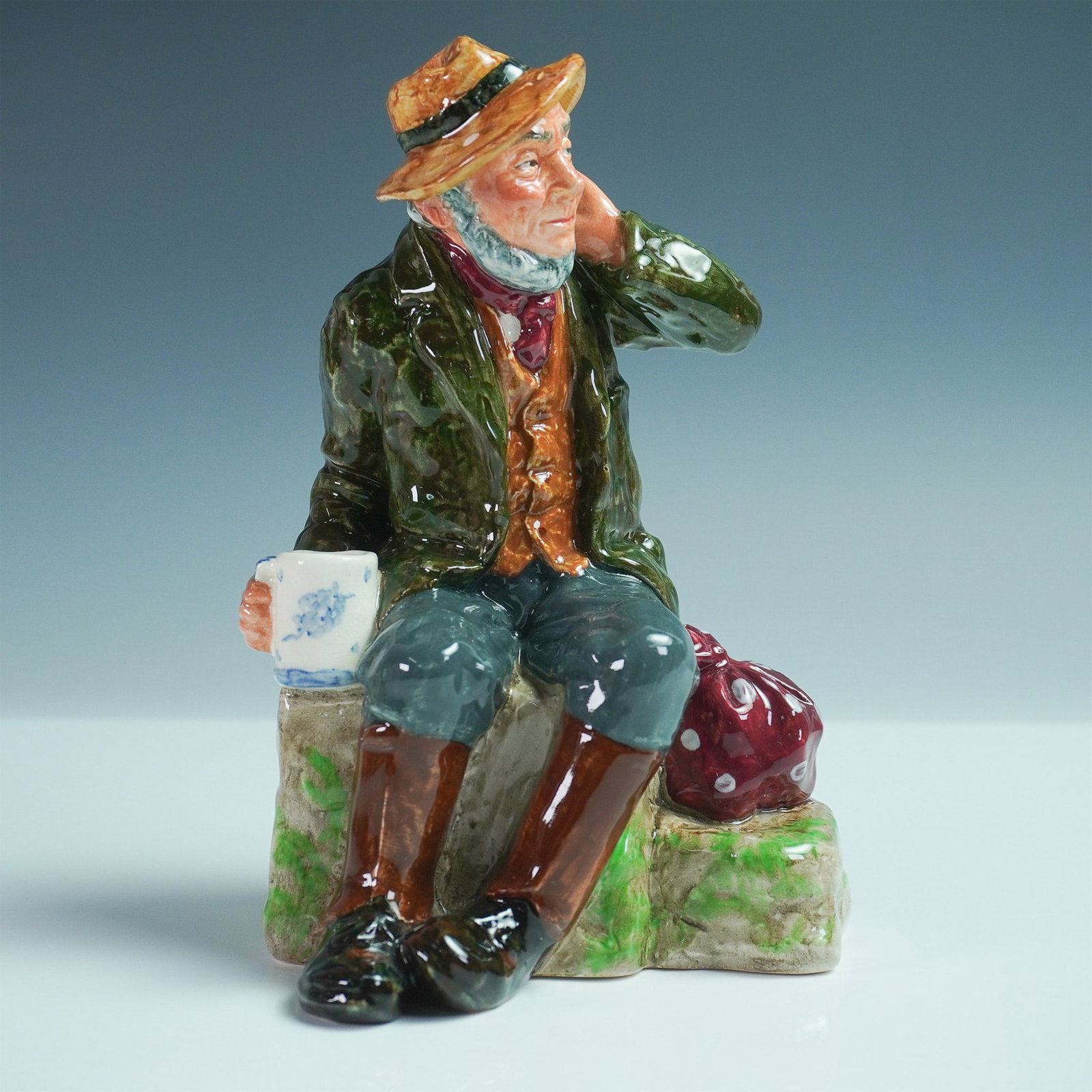 Royal Doulton Figurine Owd Willum HN2042: Royal Doulton figurine Owd Willum HN2042 is a characterful piece that portrays an elderly gentleman in a long green coat and hat, exuding a sense of nostalgia and warmth. With its detailed hand-painti