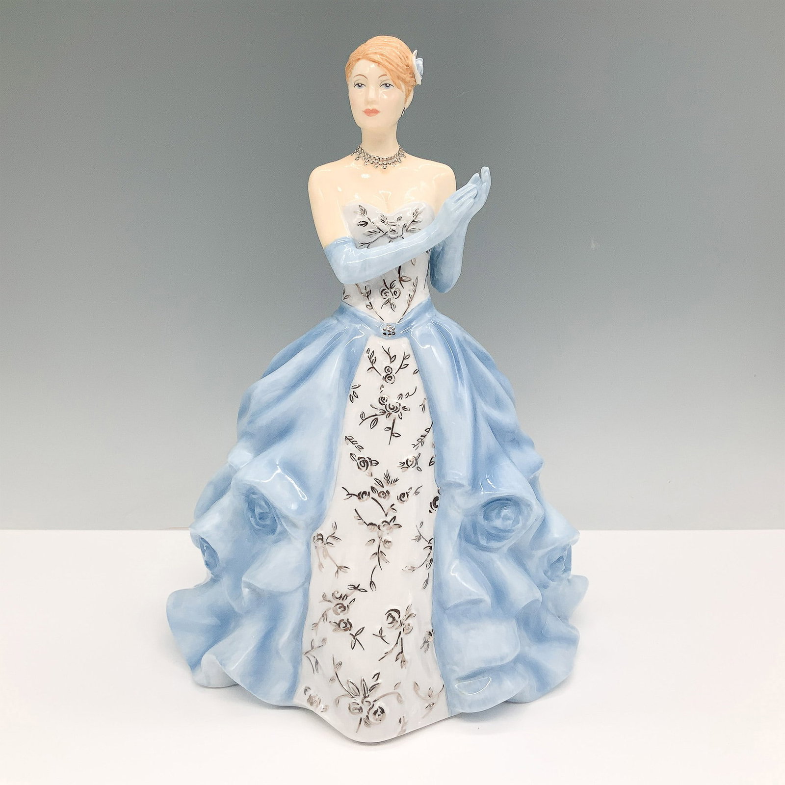 Royal Doulton Figurine, Figure of the Year Catherine HN5586: Elegant Royal Doulton bone china figurine titled Catherine, HN 5586, designated as the Figure of the Year 2013. This hand-decorated piece features a graceful lady dressed in a flowing blue gown with i