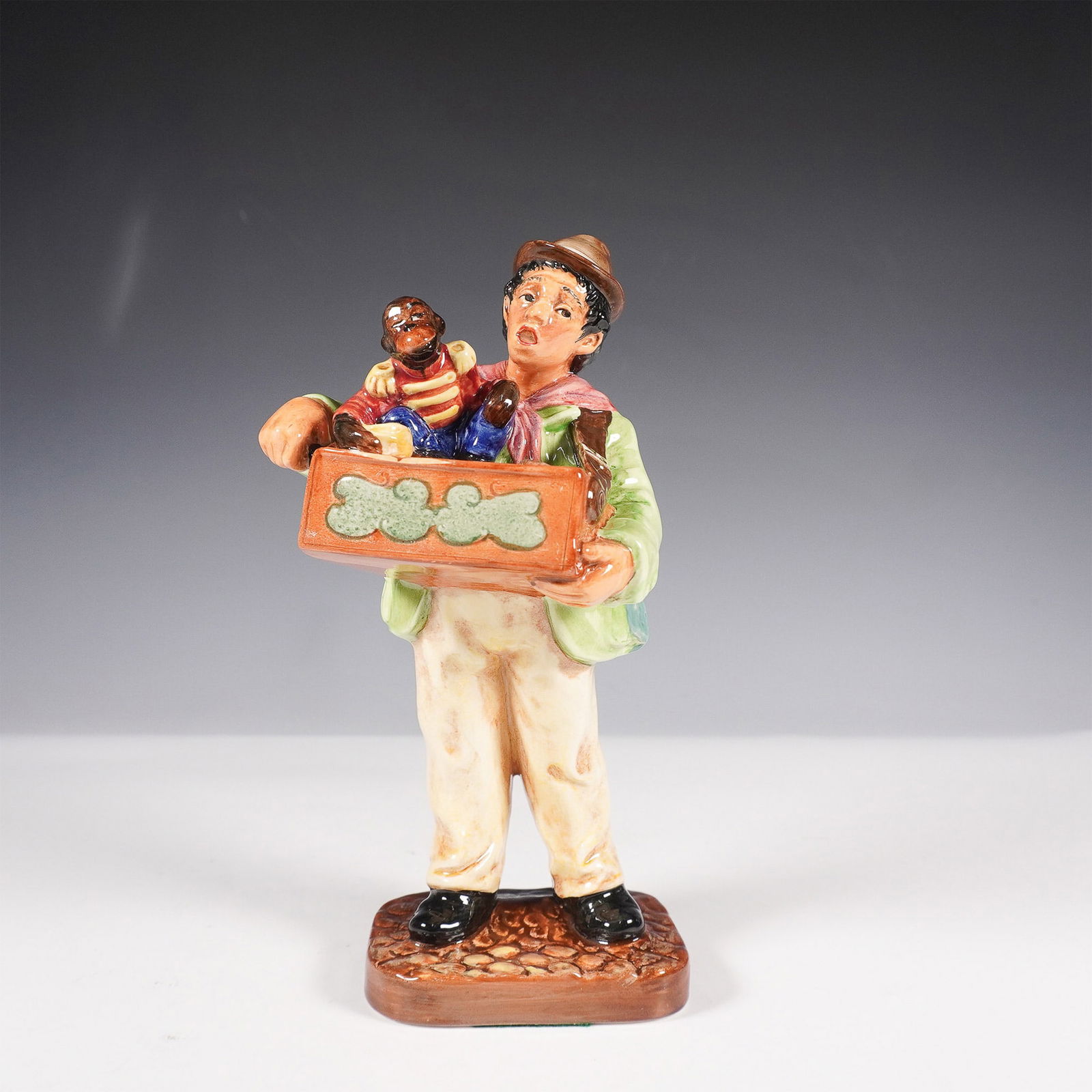 Royal Doulton Figurine, Organ Grinder HN2173: Royal Doulton figurine Organ Grinder HN2173, a delightful representation of a street musician and his companion. This fine bone china figurine, crafted in England, depicts a lively organ grinder dress