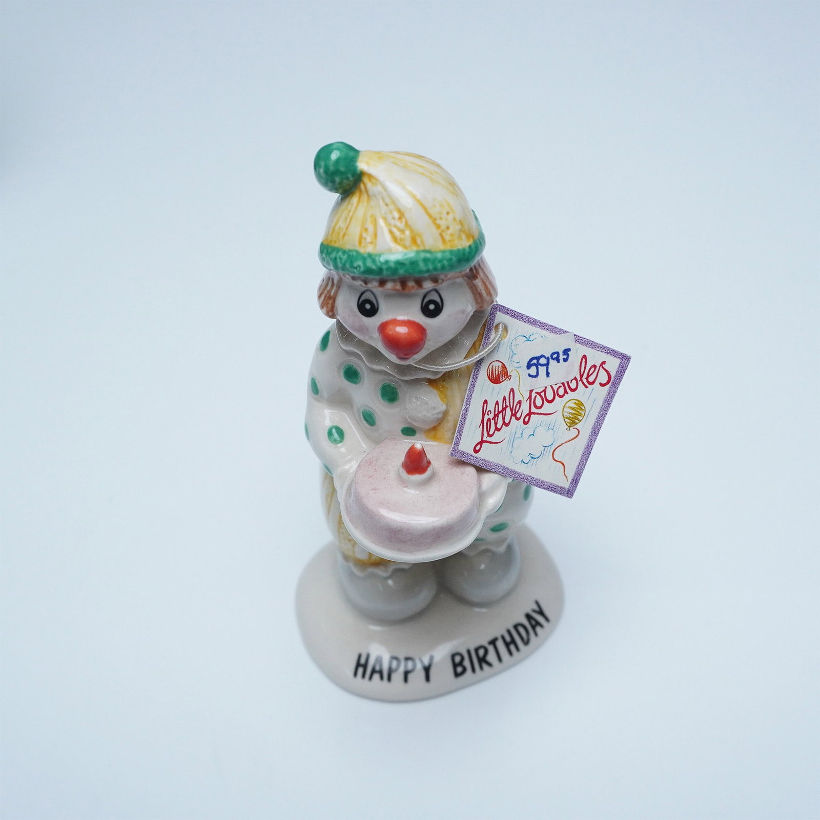 Beswick Little Lovables "Happy Birthday" Clown Figurine, LL8: A Beswick Little Lovables "Happy Birthday" clown figurine, model LL8. This hand-painted ceramic figure features a cheerful clown in green and yellow attire, holding a pink birthday cake with a single 