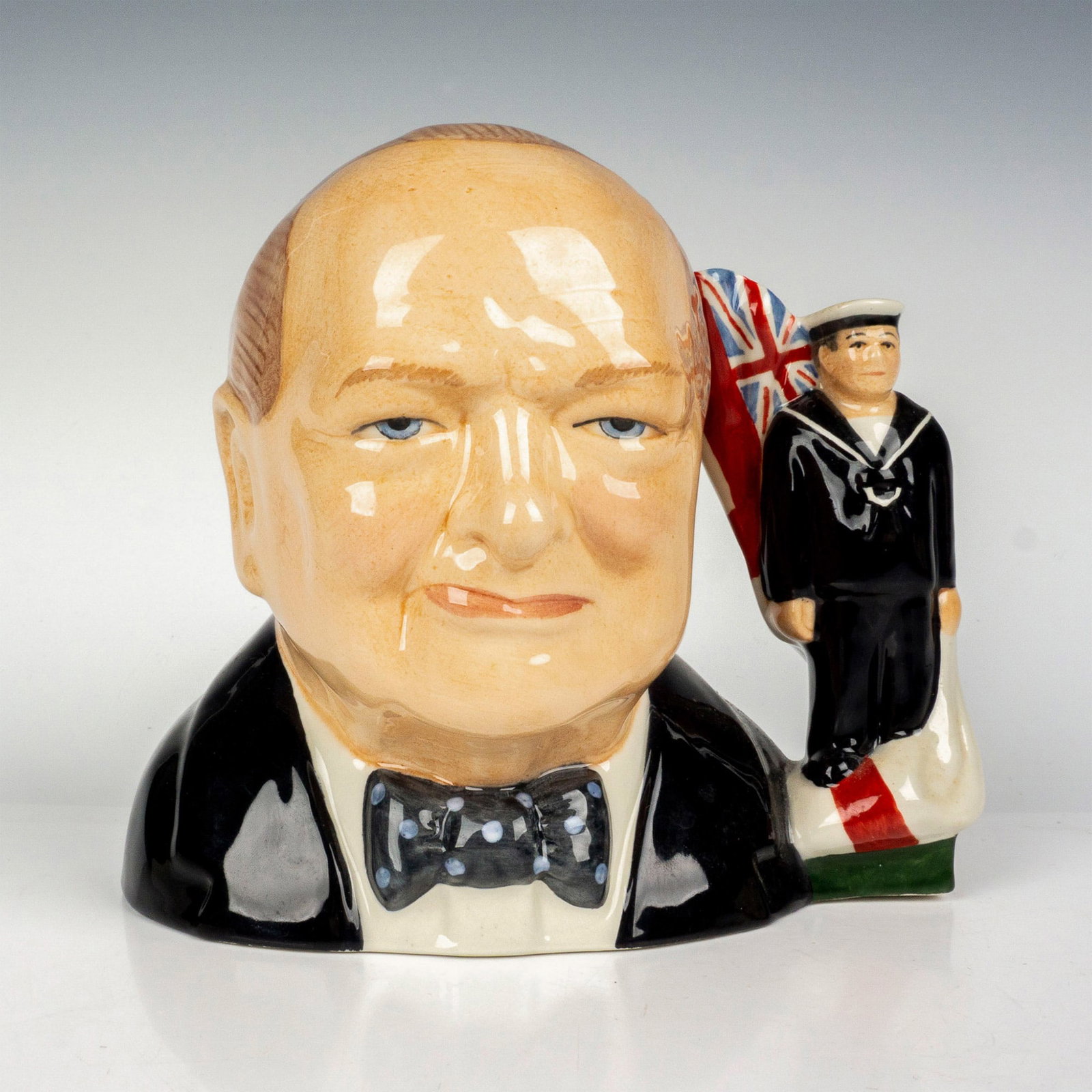 Bairstow Manor Character Jug, Winston Churchill: Limited edition featuring Prime Minister Winston Churchill Navy Forces with sailor standing in front of Navy Flag. Manor Potteries backstamp. Dimensions: 6.75"L x 4.5"W x 6.75"H Country of Origin: Eng