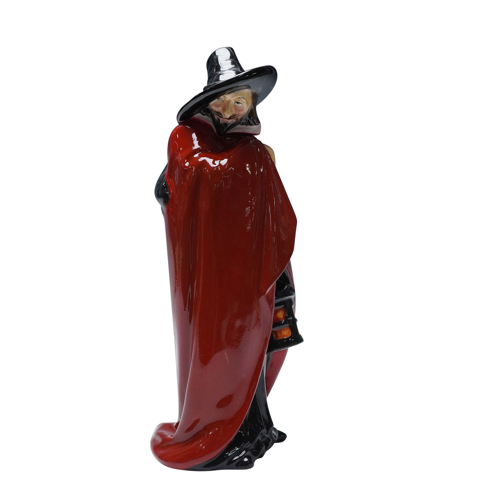 Royal Doulton Figurine, Guy Fawkes HN98: The figure is depicted standing in a black robe with a red cloak draped over his shoulders and a white collar around the neckline. He wears a black wide-brimmed hat and holds a large lantern in his ha