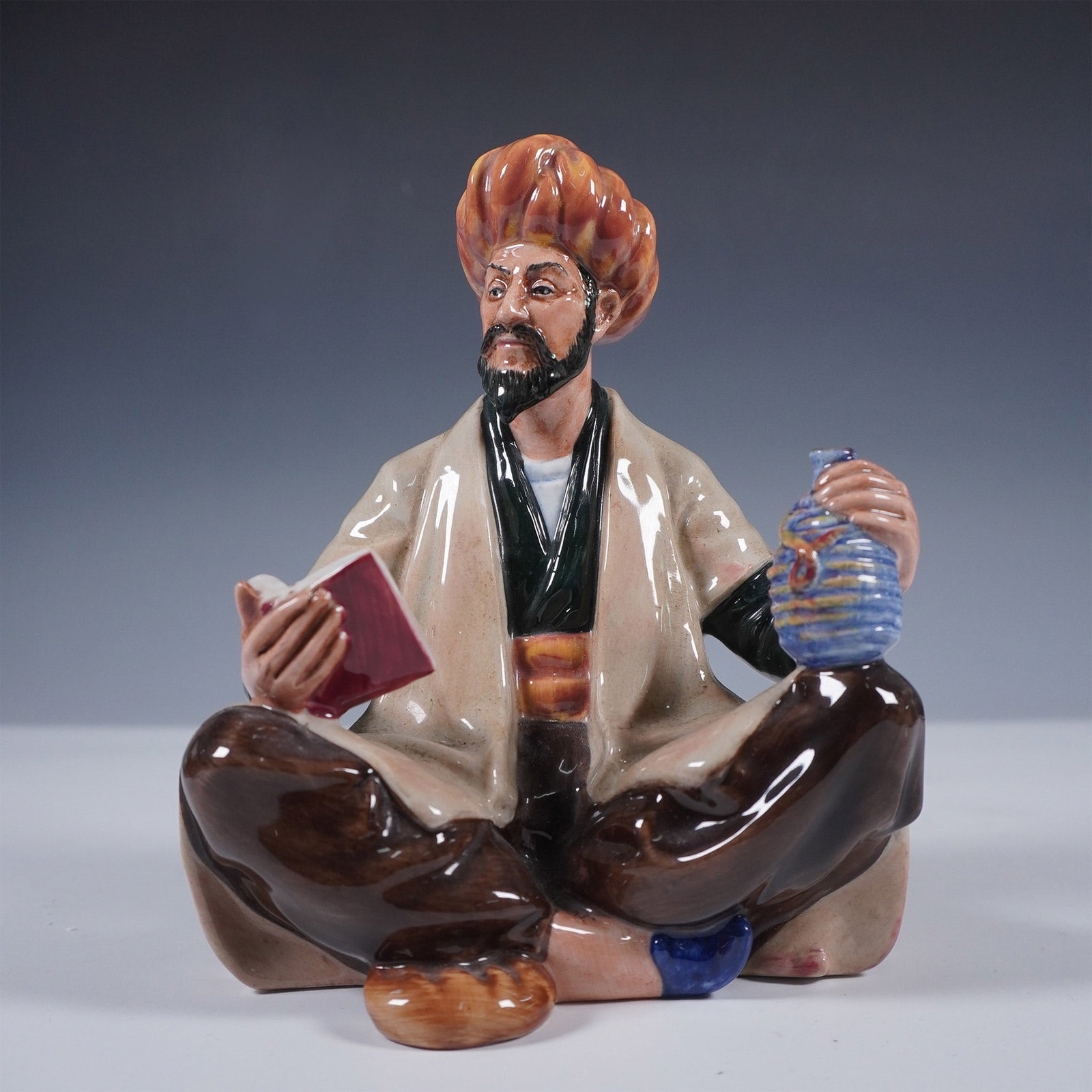 Royal Doulton Figurine, Omar Khayyam HN2247: Royal Doulton figurine titled Omar Khayyam, model HN2247, issued in 1954. This seated figure portrays the famed Persian poet and mathematician holding a book in one hand and a jug in the other, symbol